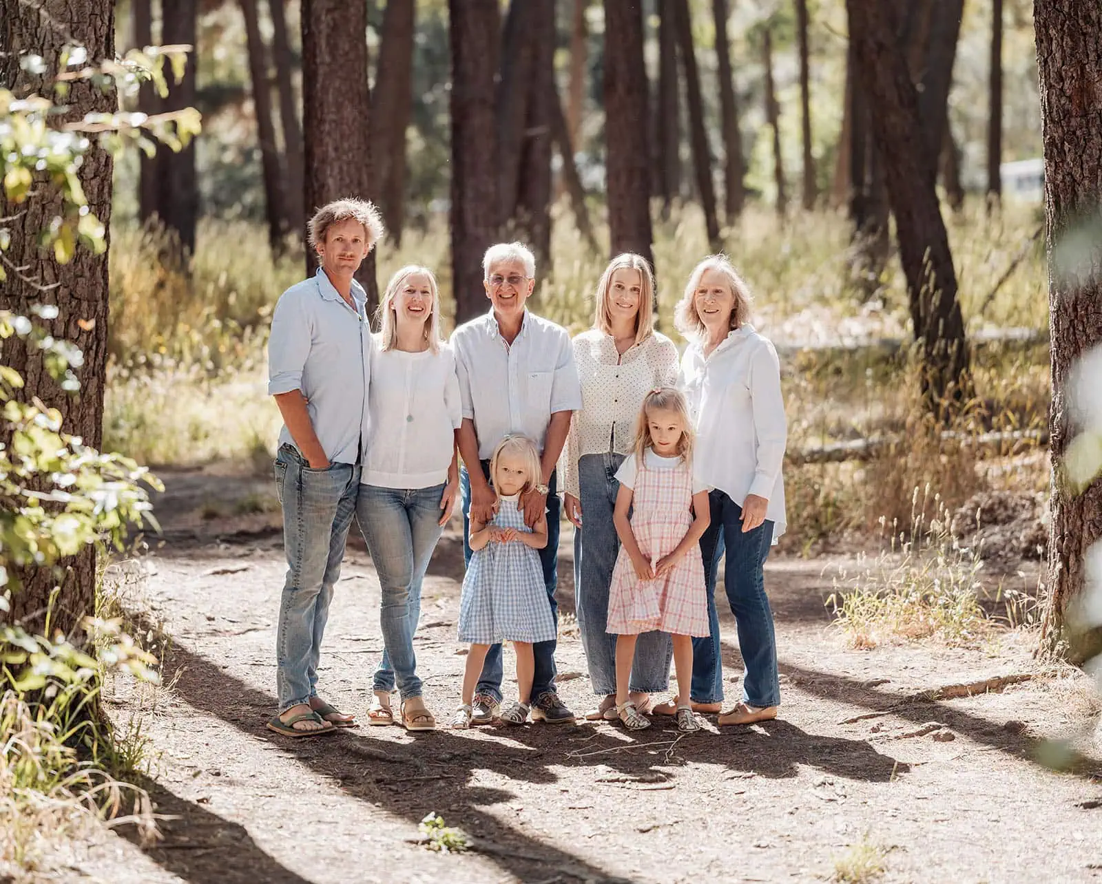 blackwood forest family photography 81 Family enjoying a sunlit forest path, surrounded by trees and dressed in light, summery colors.