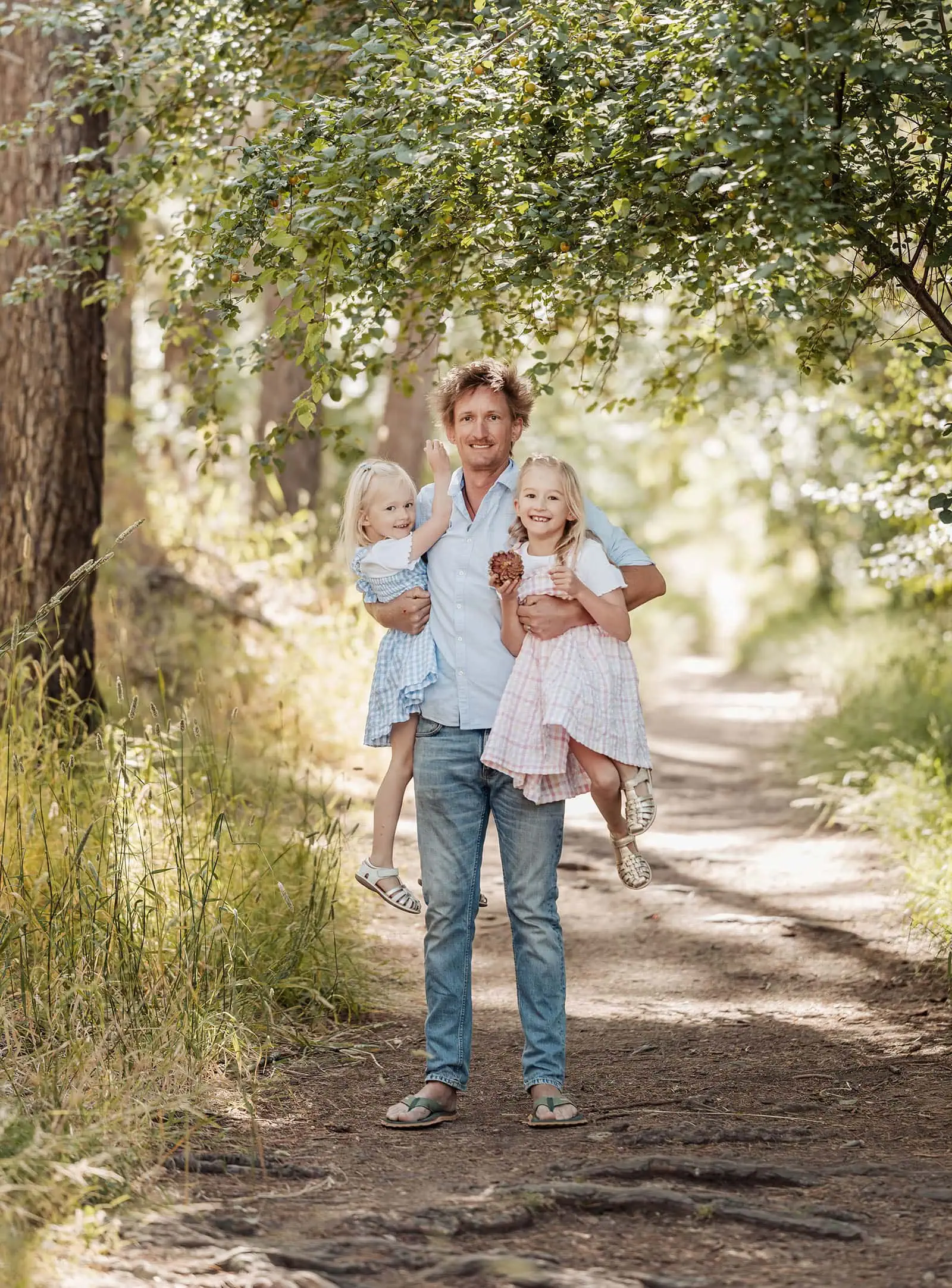 blackwood forest family photography 77 Happy family moment on a sunlit wooded path, father with daughters, natures beauty surrounds.