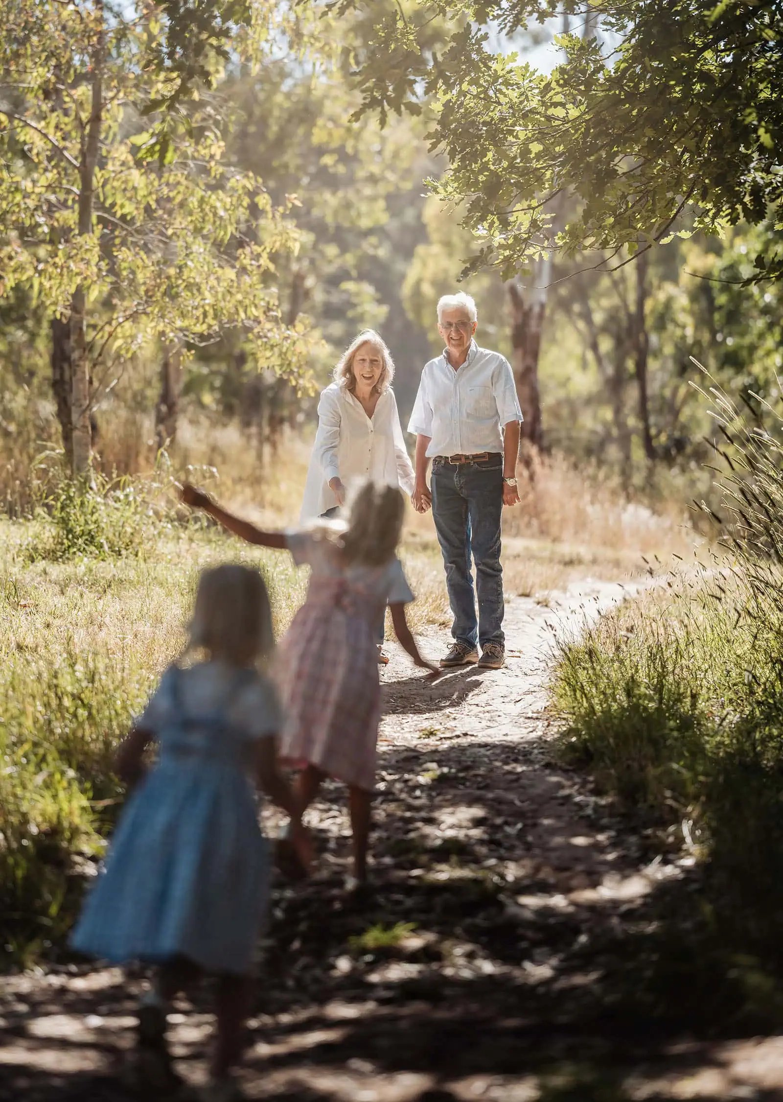 blackwood forest family photography 65 Grandchildren running to grandparents on a sunny forest path, surrounded by nature.
