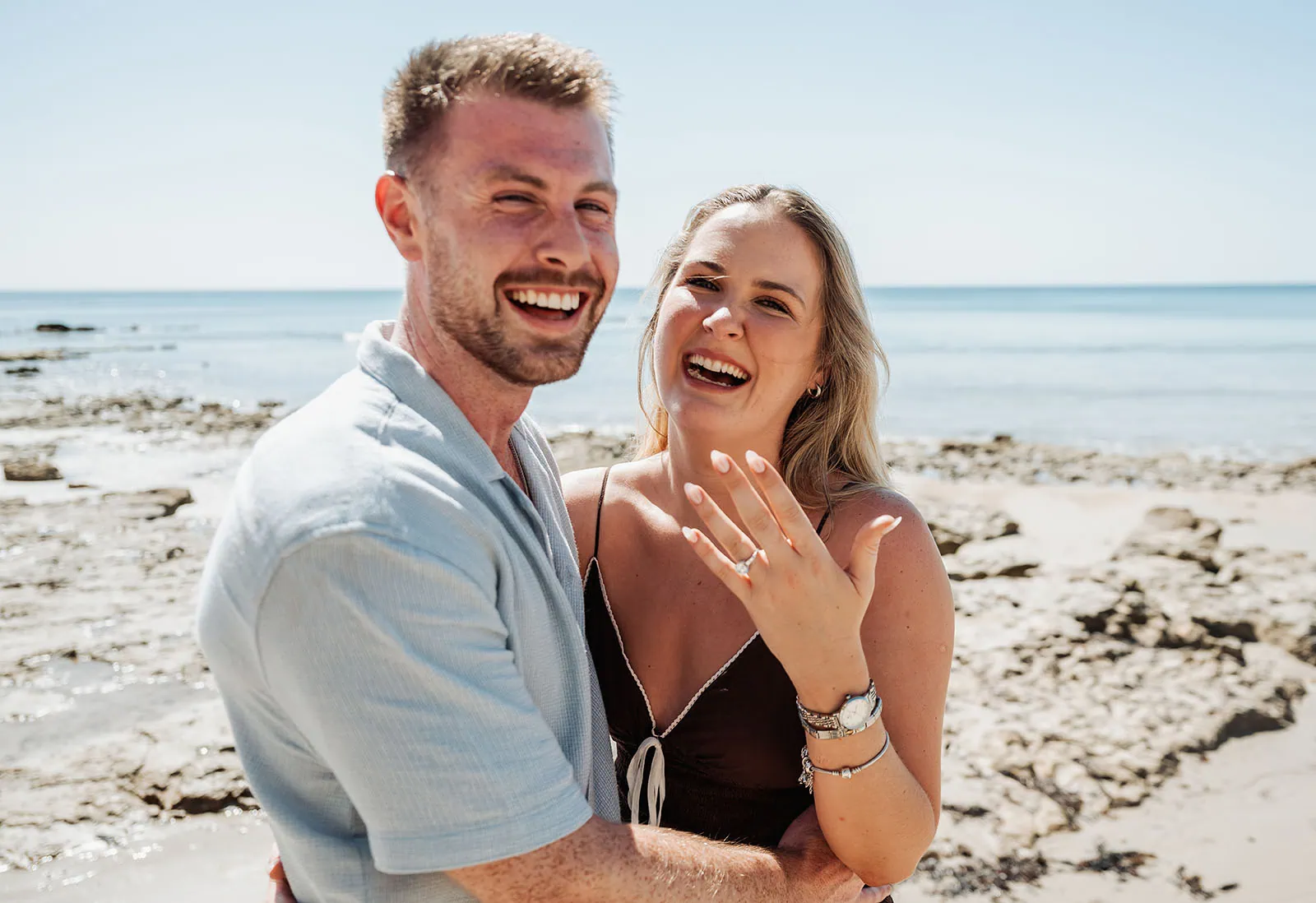 engagement rings under $2,000: 7 designs that don't look cheap 9 Engaged couple laughing on a sunny beach, showcasing ring and love.