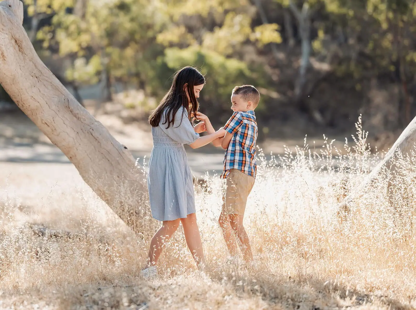 beautiful anstey hill family photoshoot 9 Children playing joyfully in sunlit field, wearing colorful clothes, surrounded by natures beauty.
