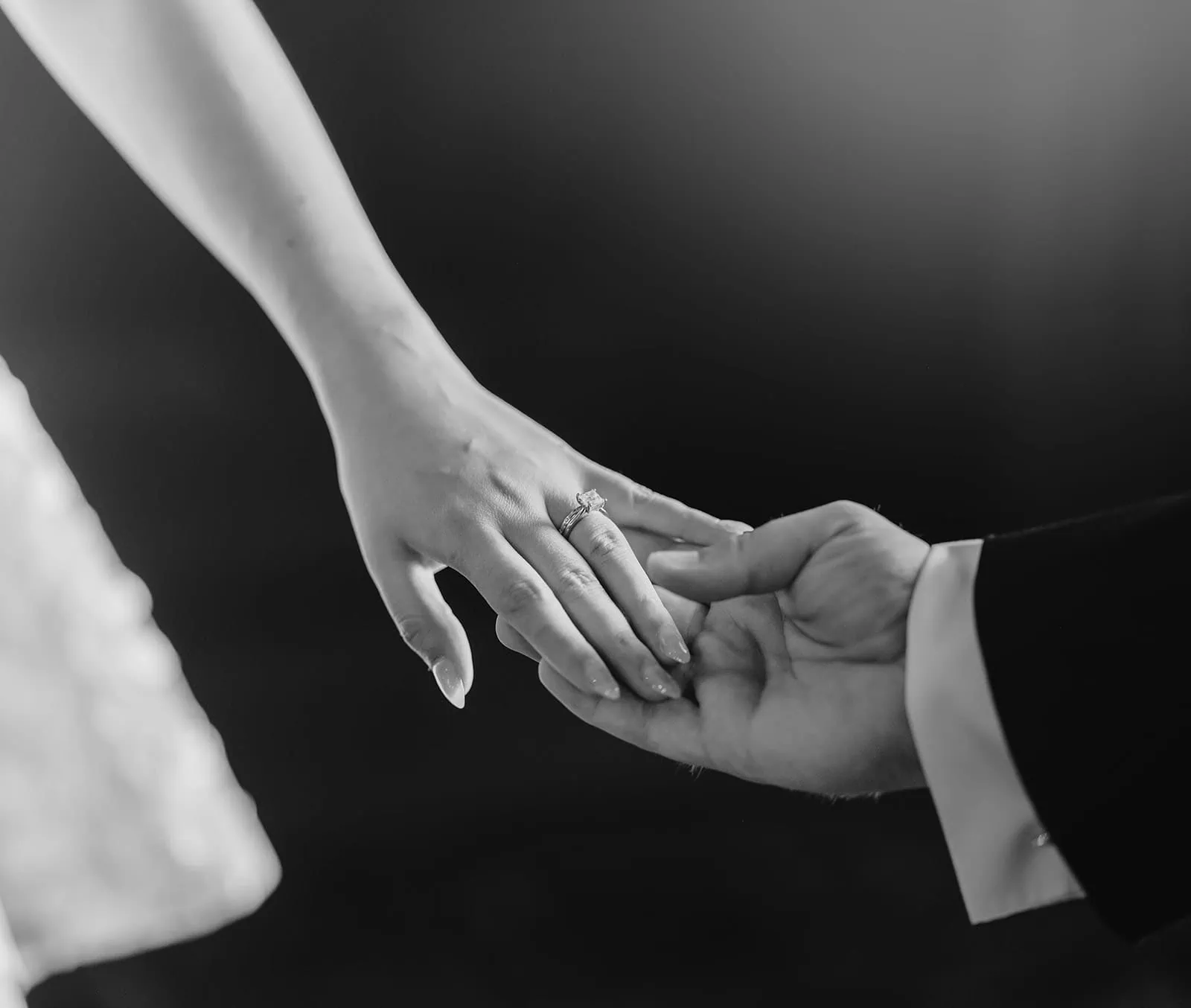 engagement rings under $2,000: 7 designs that don't look cheap 10 Elegant hands intertwine, highlighting a sparkling engagement ring in a timeless black and white photograph.