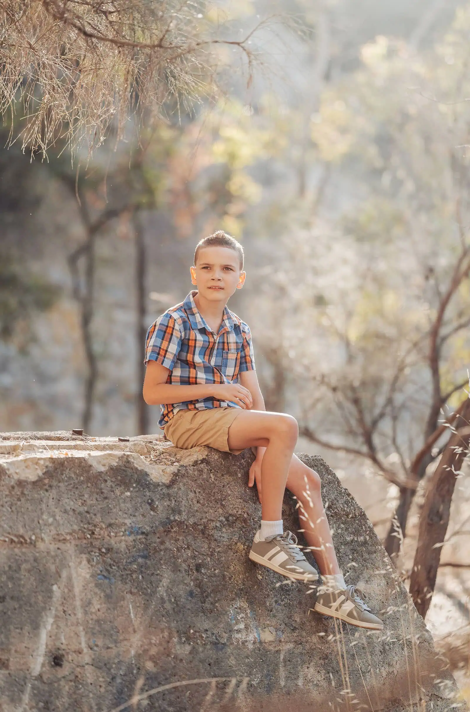 beautiful anstey hill family photoshoot 12 Young boy on a rock in a serene forest setting observing nature.