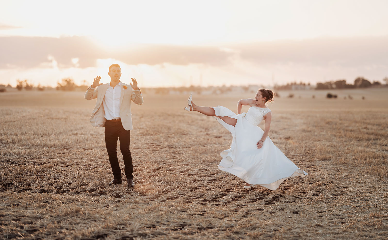 documentary perth wedding photography by svenstudios 14 Bride playfully kicks groom in sunset field, capturing joyful, romantic wedding moment.