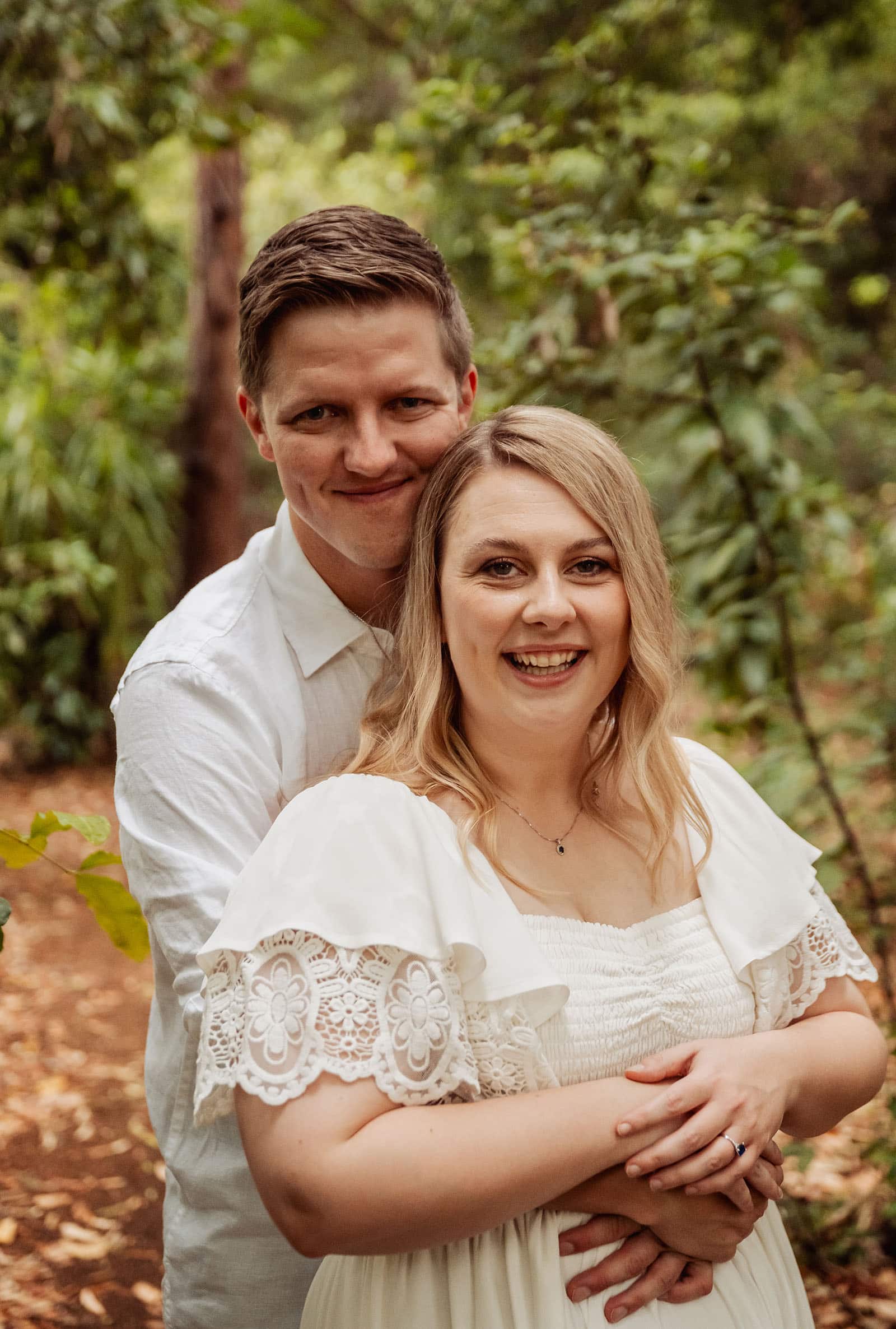 botanic gardens wedding shoot - olivia & sean 25 Couple embracing in sunlit, lush greenery, conveying love and tranquility outdoors.