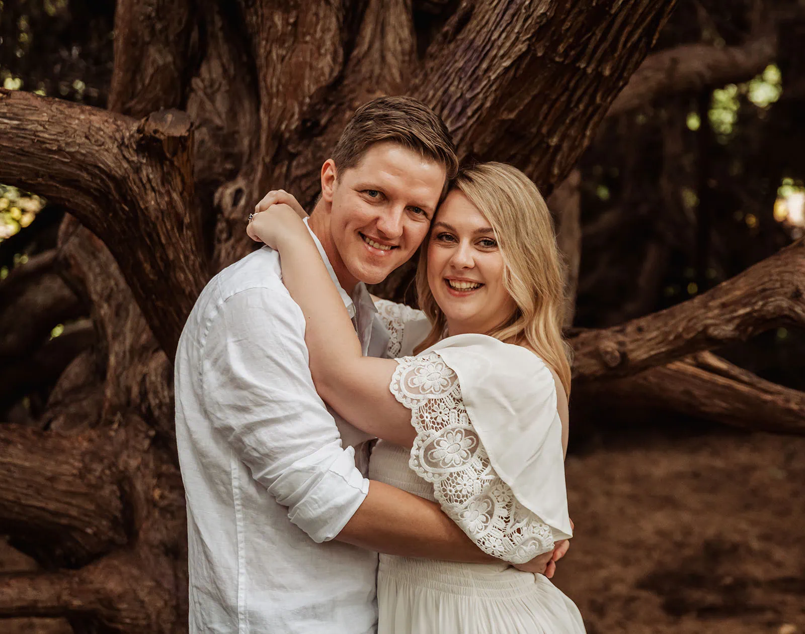 botanic gardens wedding shoot - olivia & sean 21 Joyful couple embracing under a tree in a serene, romantic wooded setting.