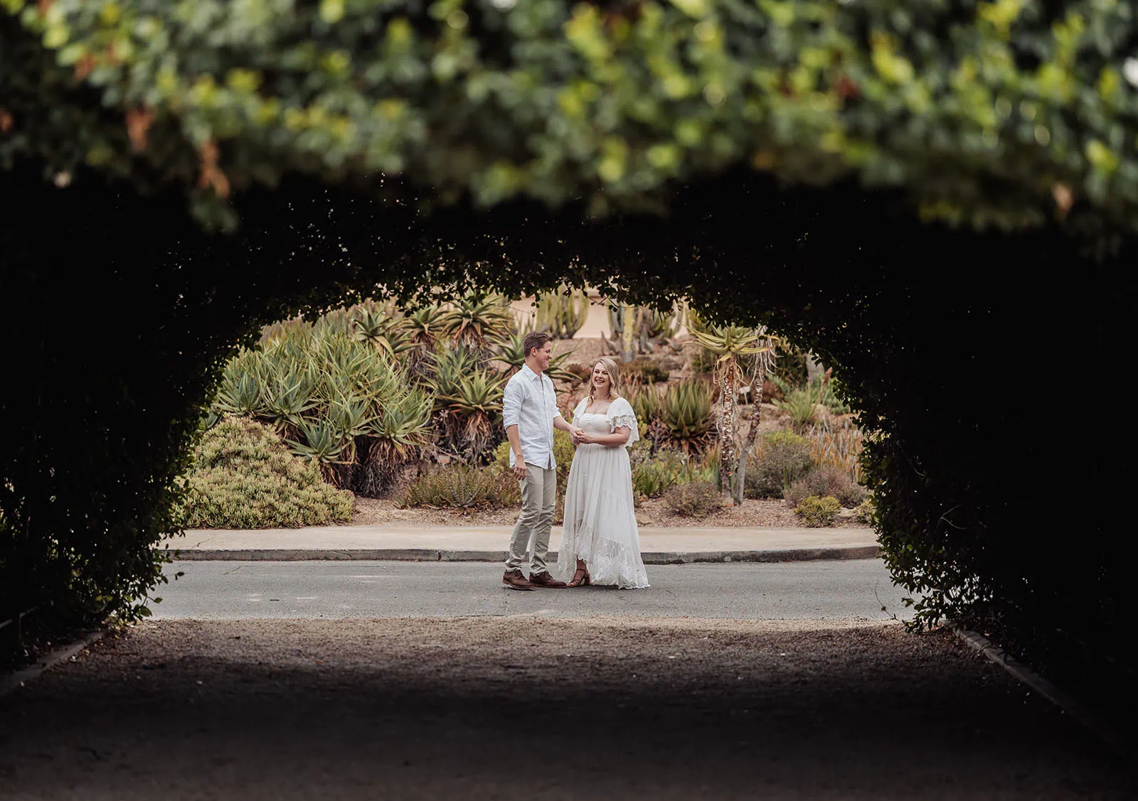 botanic gardens wedding shoot - olivia & sean 7 Romantic couple framed by a lush green arch in a serene botanical garden.