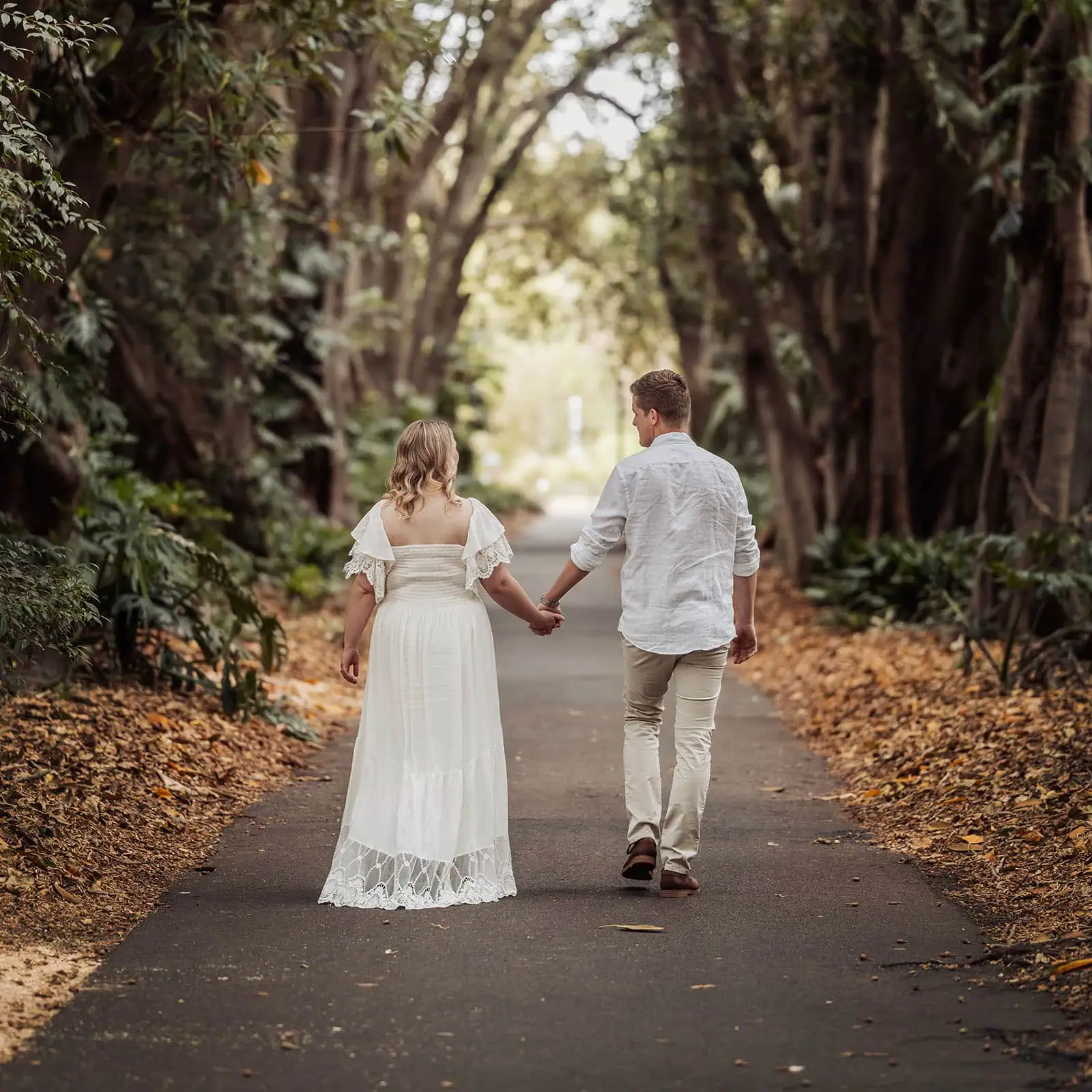 botanic gardens wedding shoot - olivia & sean 1 Couple walking hand in hand on tree-lined path, serene fall foliage.