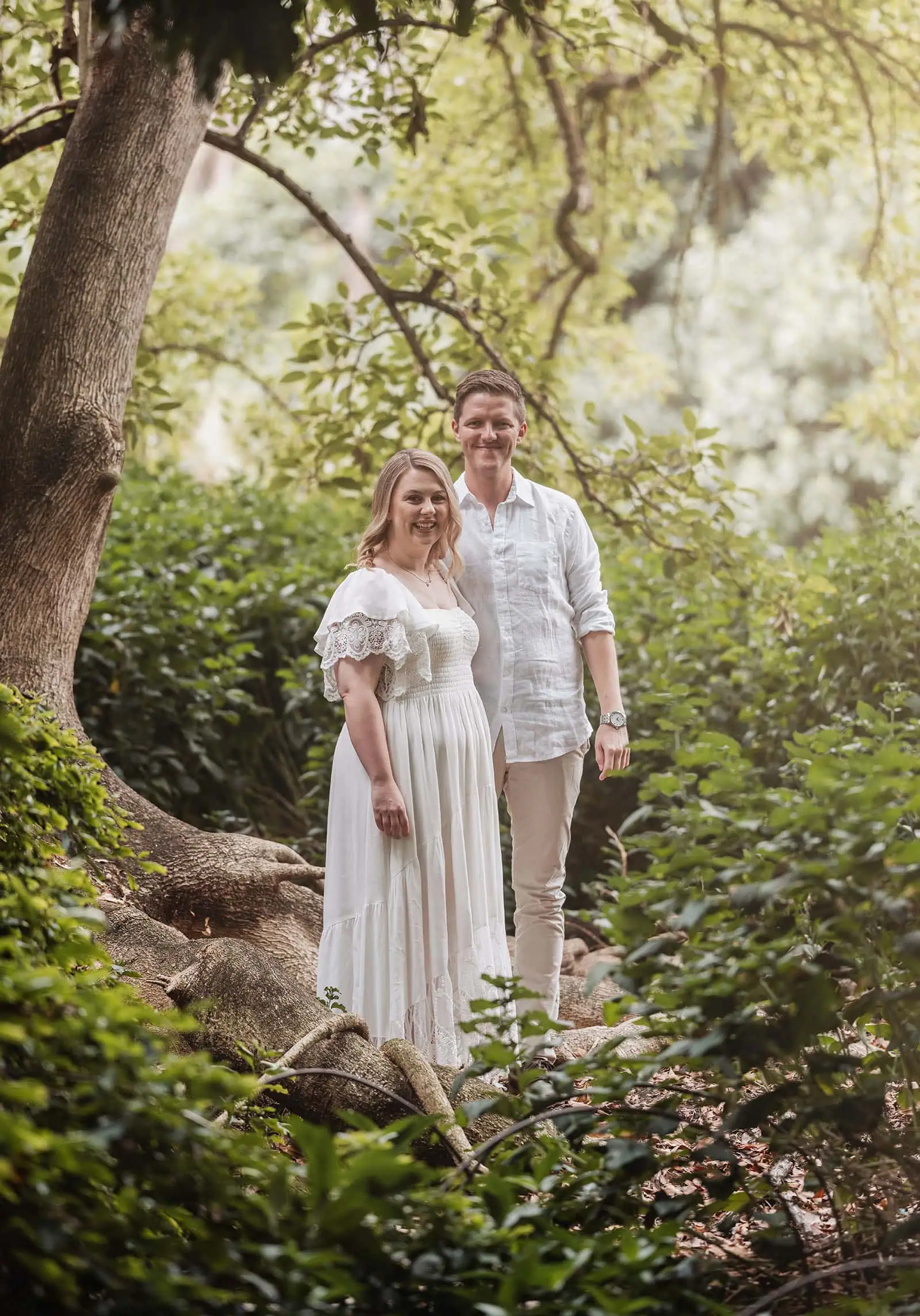 botanic gardens wedding shoot - olivia & sean 3 Romantic couple in serene forest setting with sunlight, tree, and lush greenery.