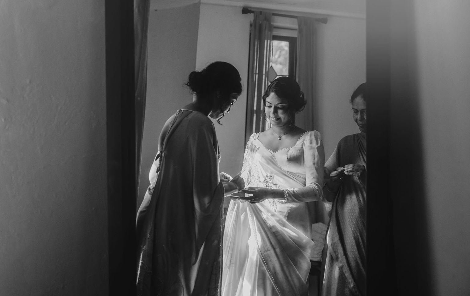 manor wedding in basket range - methmini & aravinda 116 Bride in sari, women assisting, intimate preparation before wedding celebration.