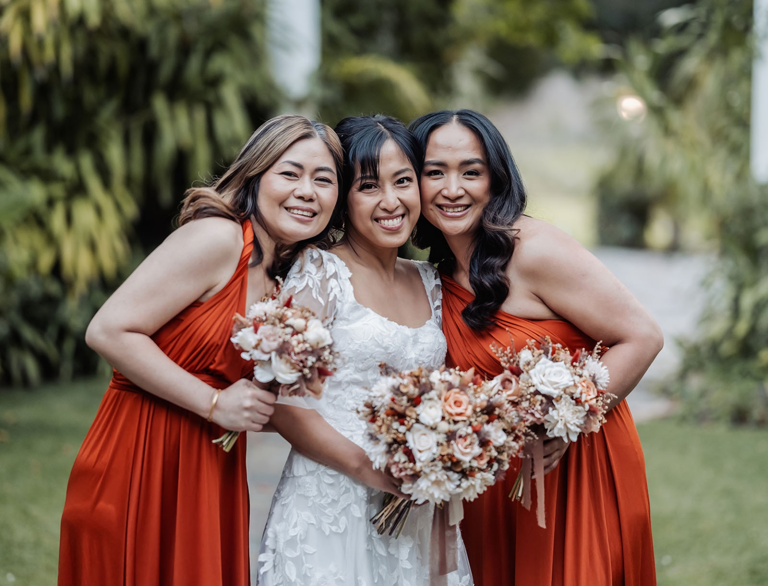 adelaide hills wedding at the manor - jo & dan 41 Bride with bridesmaids in rust orange dresses holding bouquets at garden wedding.