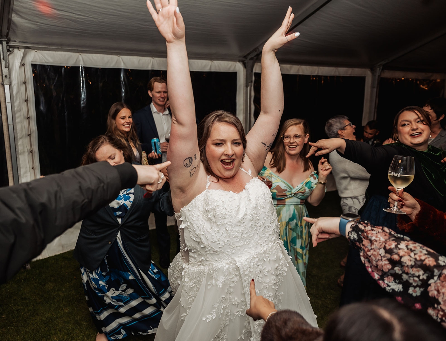 comida wedding - georgia & james 52 Bride celebrating joyfully with guests at tented wedding reception.