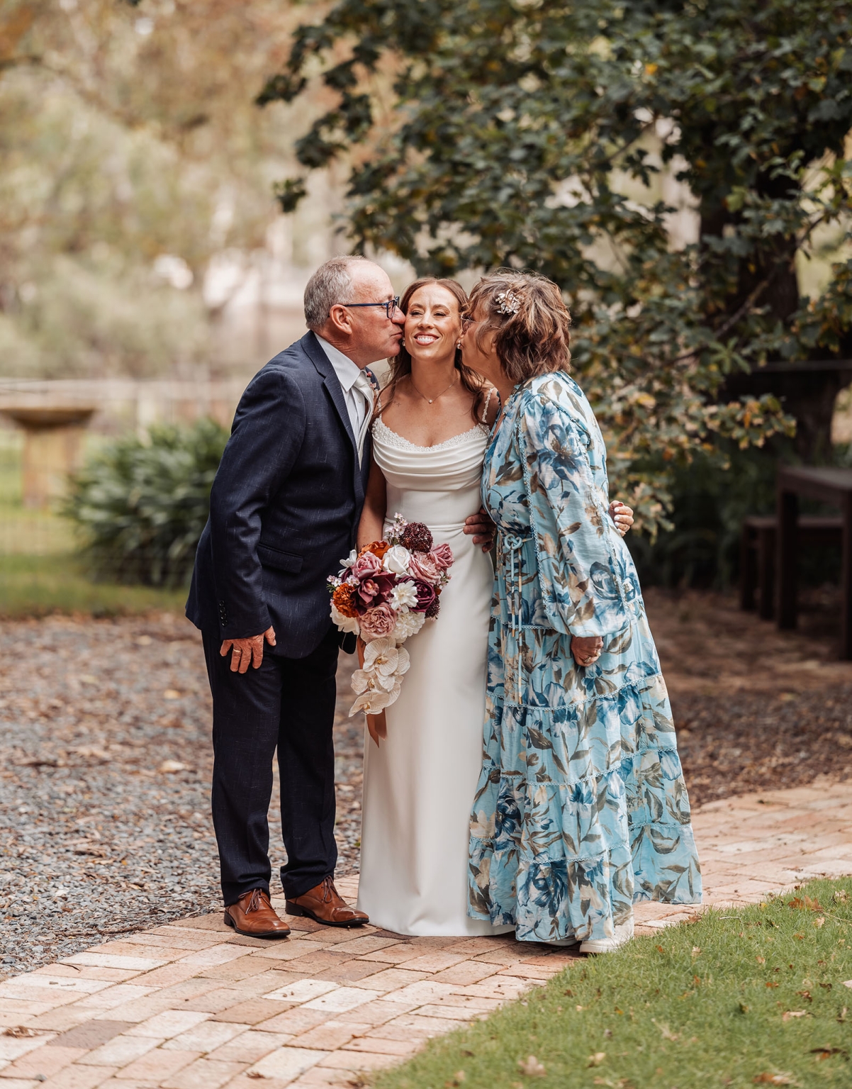 the lane vineyard wedding - caitlyn & craig 98 Bride with parents sharing a joyful moment at outdoor wedding celebration.