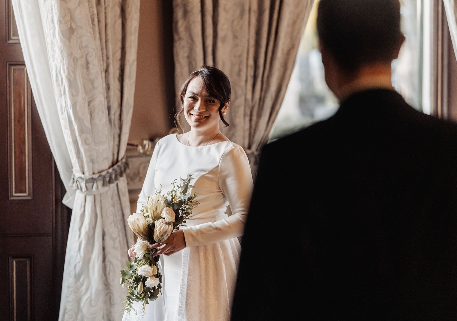 adelaide's st peter's cathedral wedding - irish & nick 42 Bride during emotional first look wedding holding bouquet in elegant room.