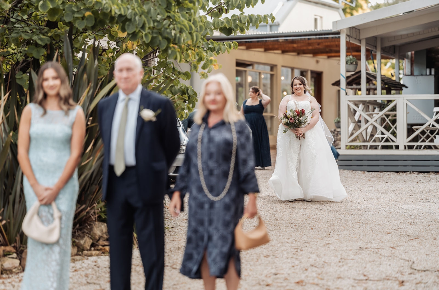 comida wedding - georgia & james 9 Bride joyfully walks in a lace gown with bouquet at outdoor garden wedding.