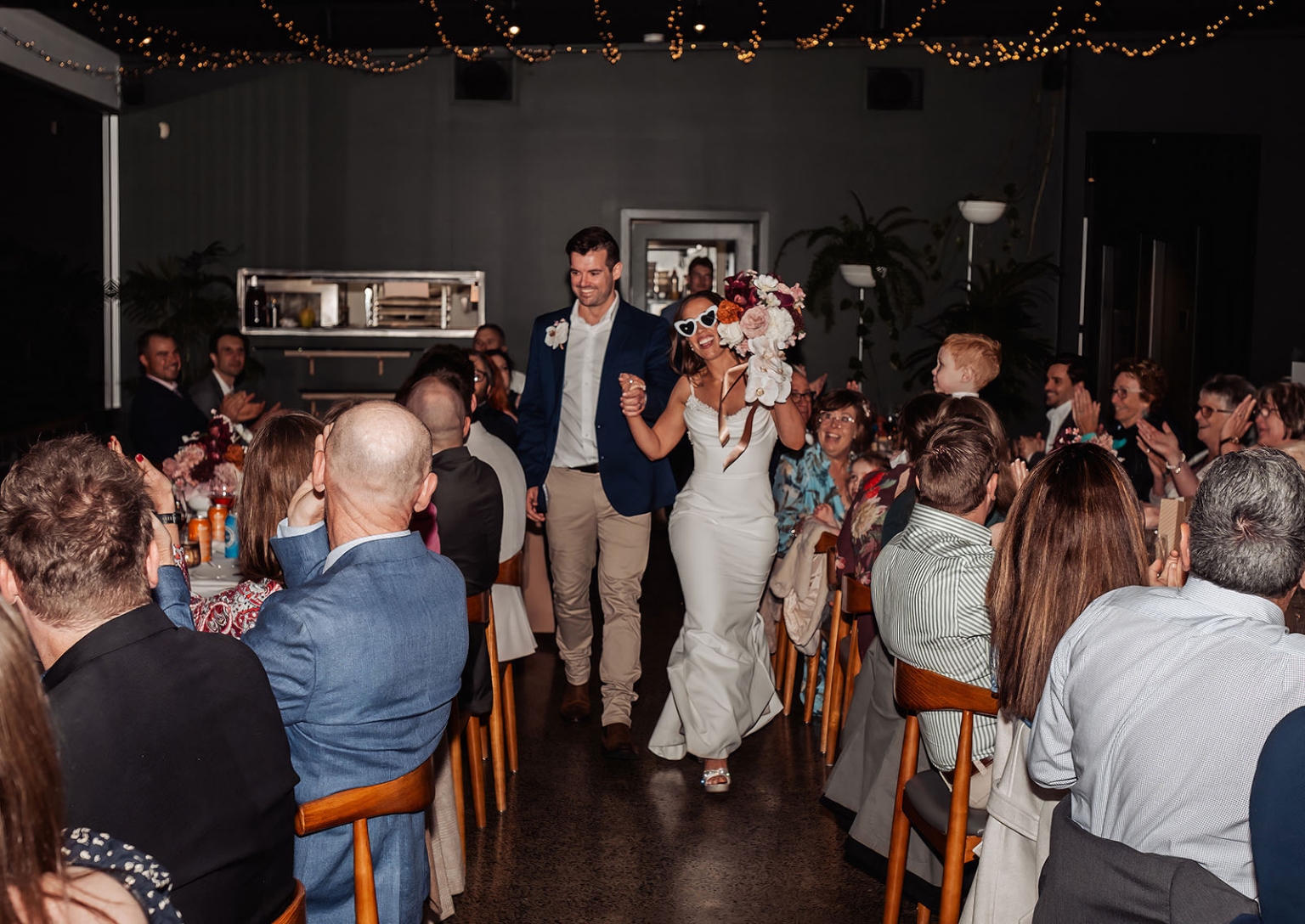the lane vineyard wedding - caitlyn & craig 131 Bride and groom entrance at reception with joyful guests, elegant decor, and romantic lighting.