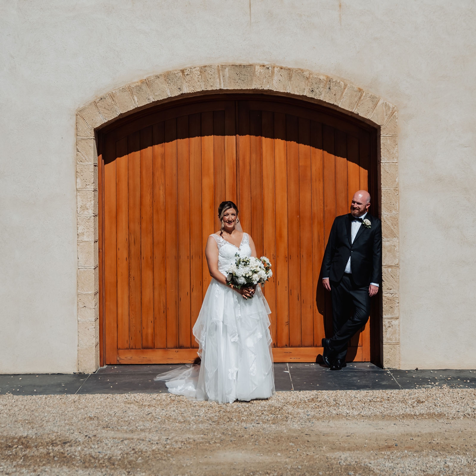 lloyd brothers wedding - dajana & tom 25 Bride and groom smiling in front of rustic wooden doors on wedding day.