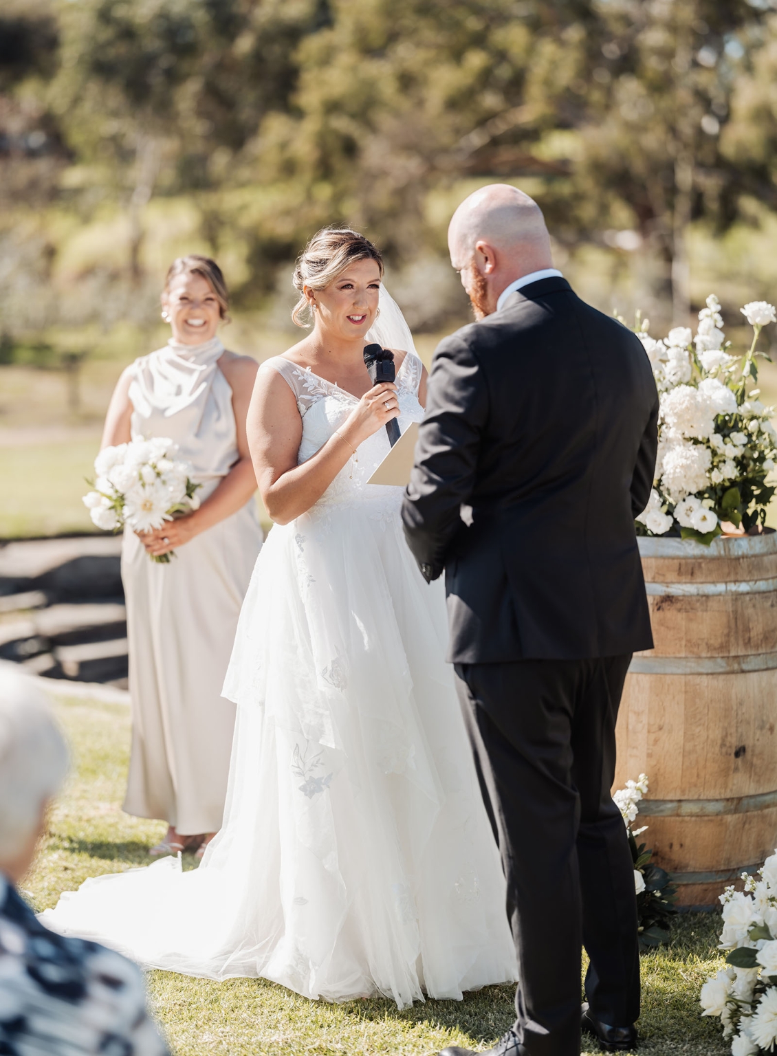 lloyd brothers wedding - dajana & tom 16 Bride recites vows in garden ceremony with bridesmaid and groom.
