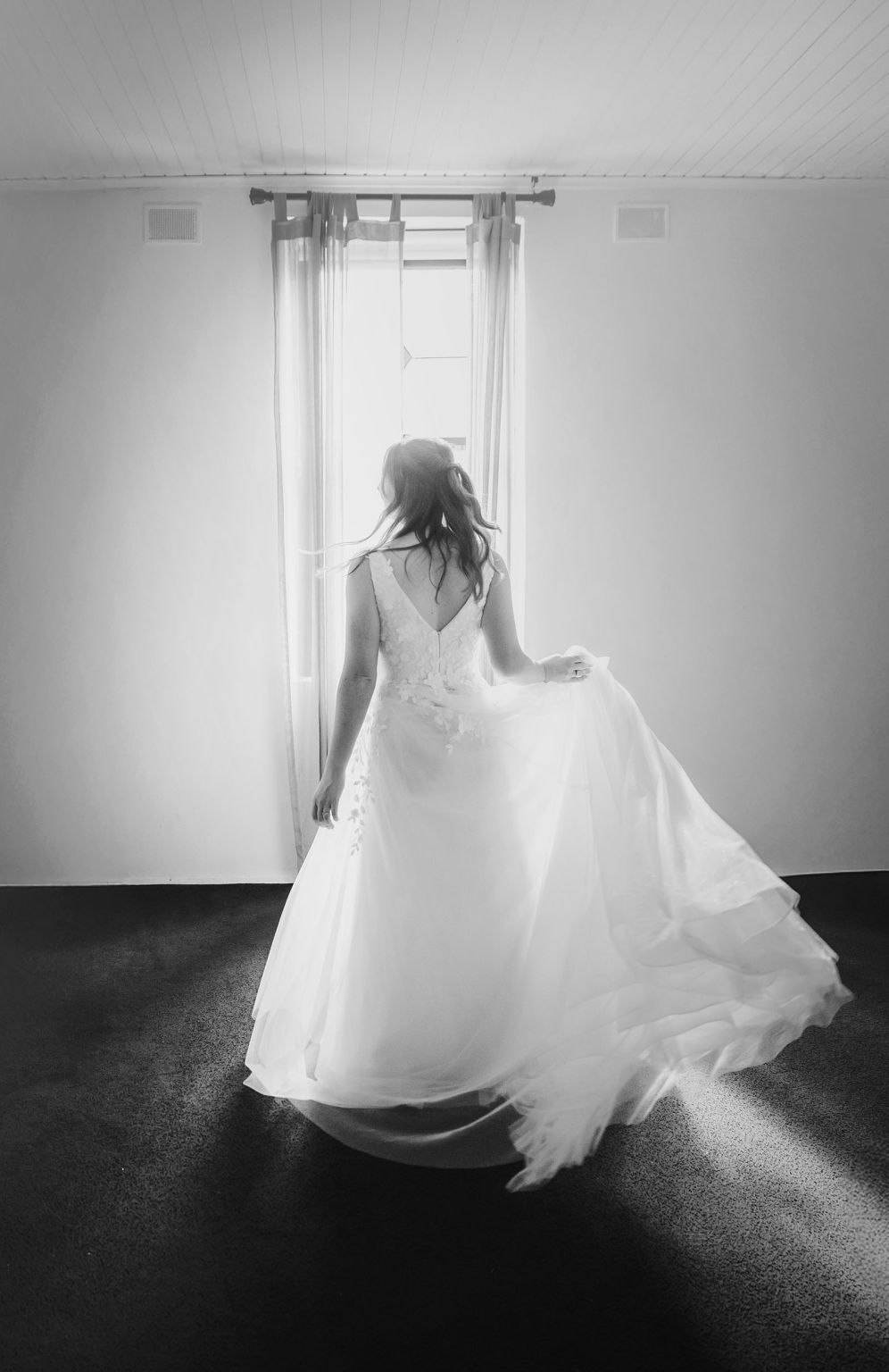 beautiful manor basket range wedding - sophie & theodore 94 Bride in flowing gown stands in window light, exuding elegance and serenity.