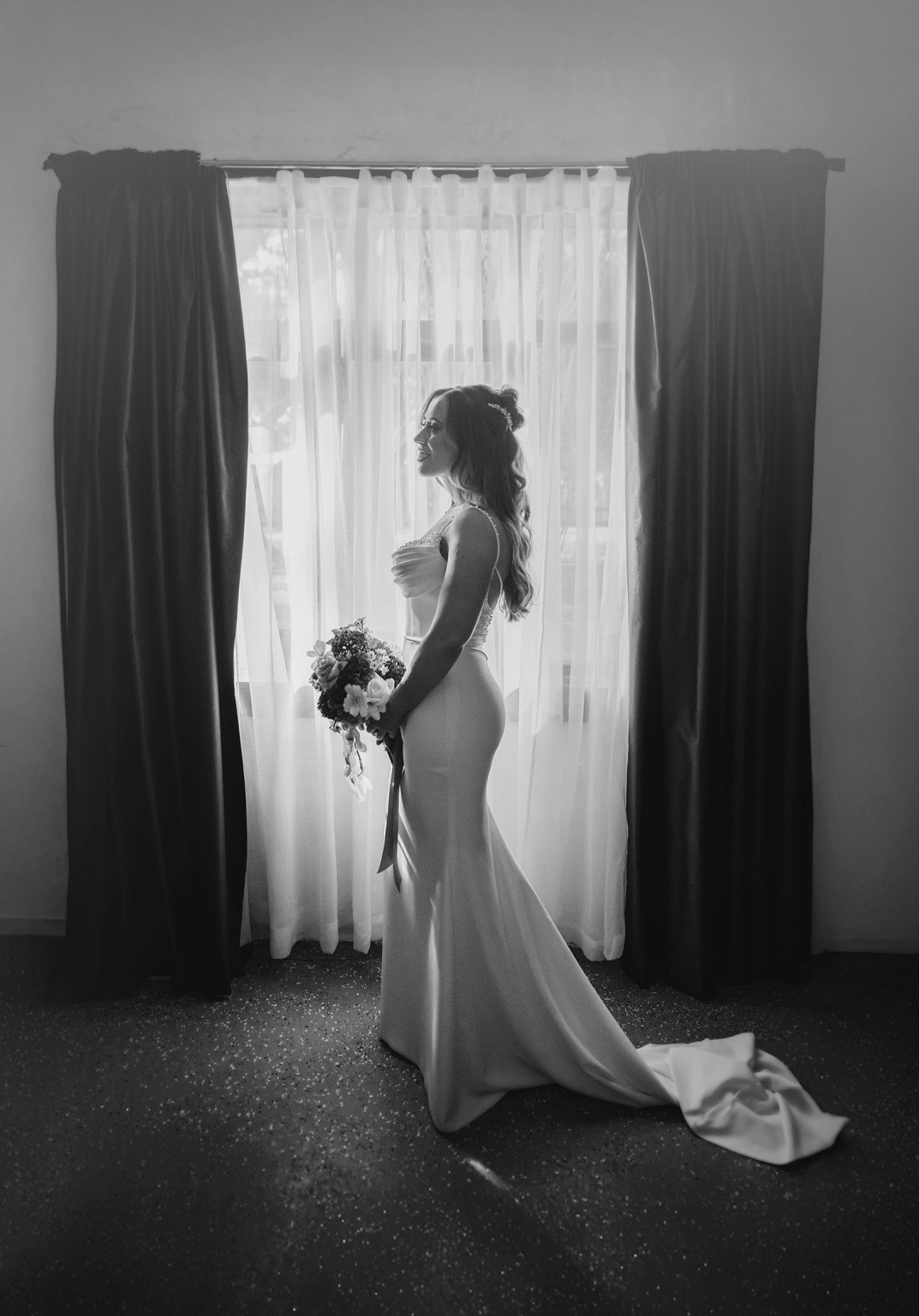 the lane vineyard wedding - caitlyn & craig 92 Bride silhouetted in elegant wedding gown by softly lit window with bouquet.