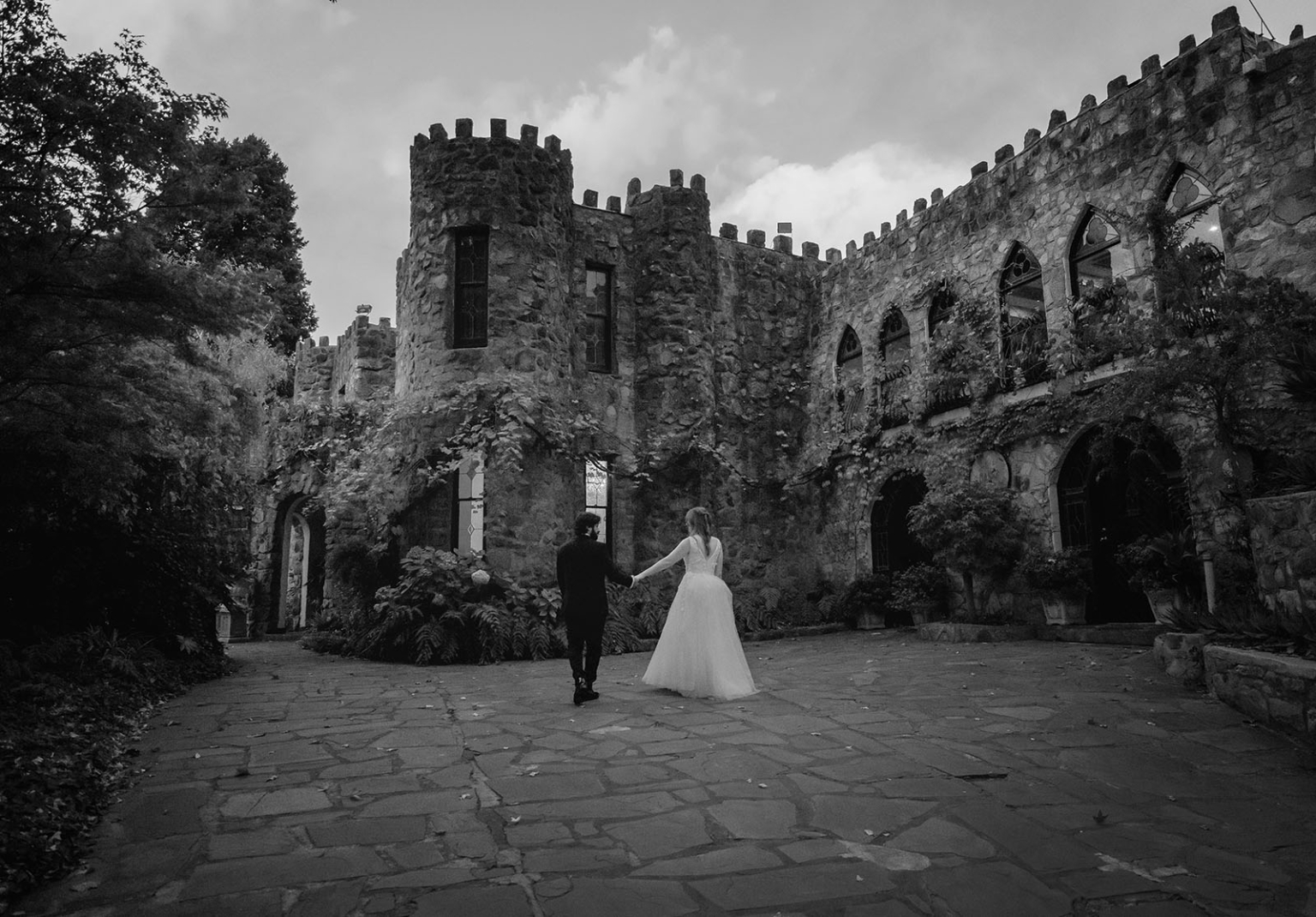 beautiful manor basket range wedding - sophie & theodore 137 Bride and groom walk hand in hand towards a medieval castle.