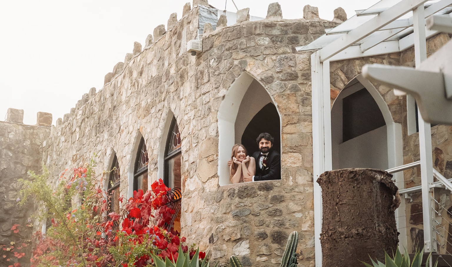 beautiful manor basket range wedding - sophie & theodore 136 Couple in Gothic window, stone castle, with vibrant flowers and greenery.