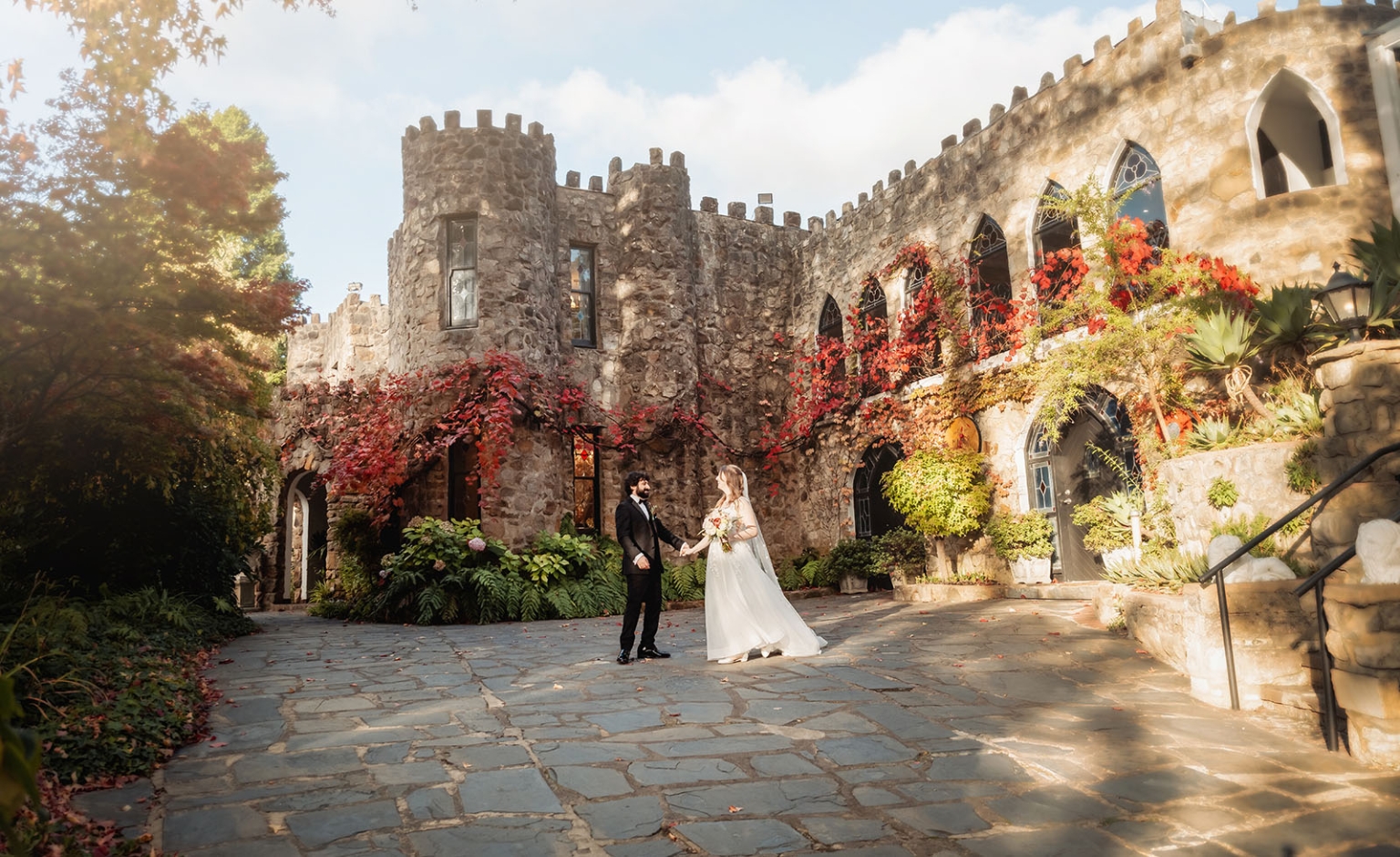 beautiful manor basket range wedding - sophie & theodore 119 Bride and groom at a castle wedding, surrounded by vibrant flowers and medieval architecture.