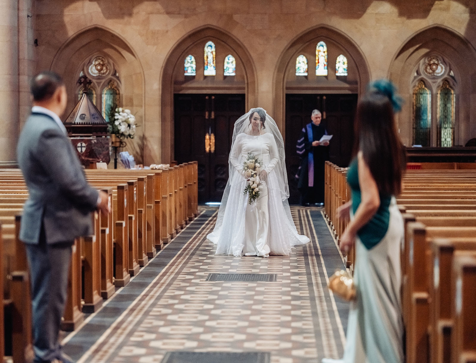 adelaide's st peter's cathedral wedding - irish & nick 14 Bride in white gown walking down Gothic church aisle during wedding ceremony.