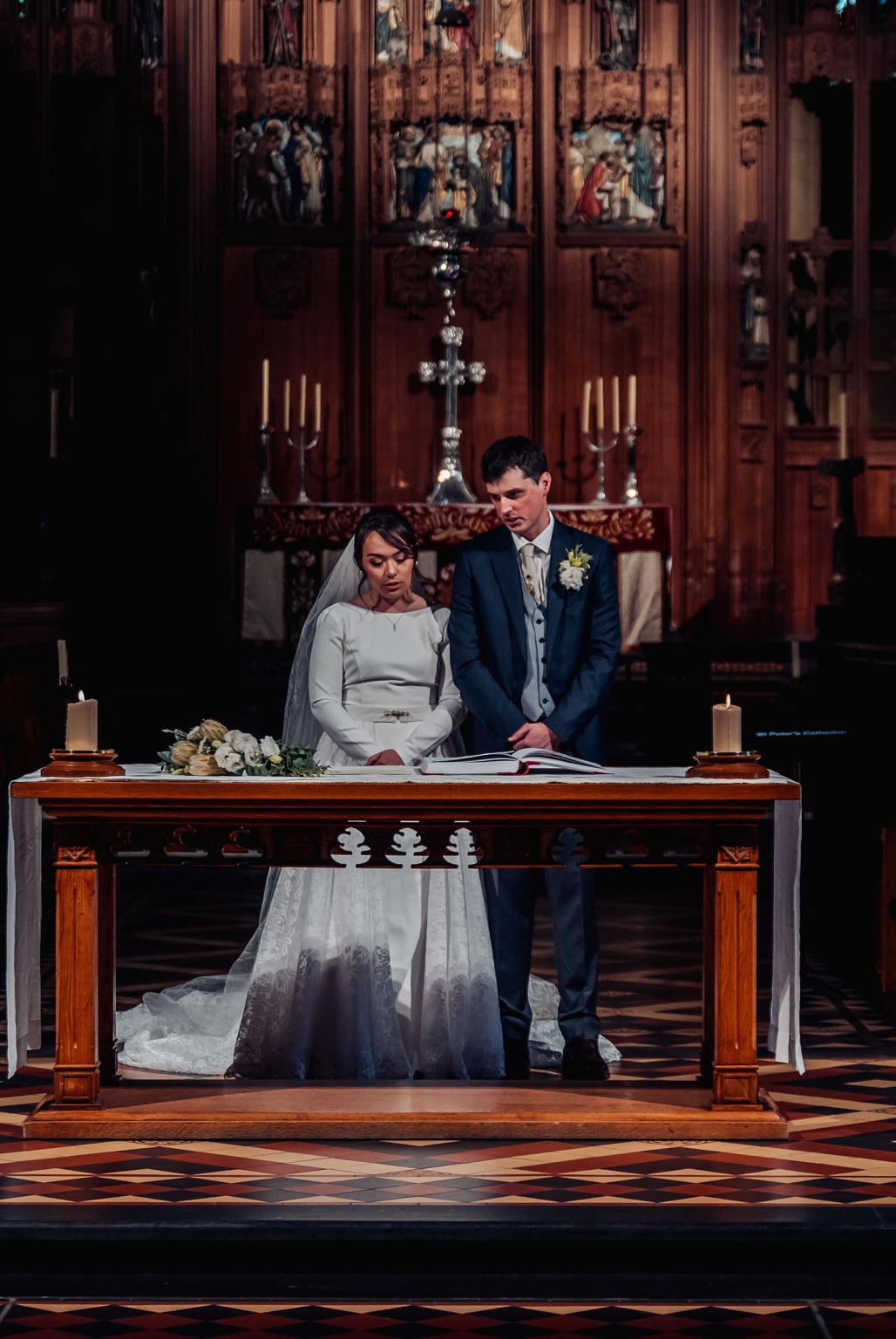 adelaide's st peter's cathedral wedding - irish & nick 28 Bride and groom at church altar during a candlelit wedding ceremony.