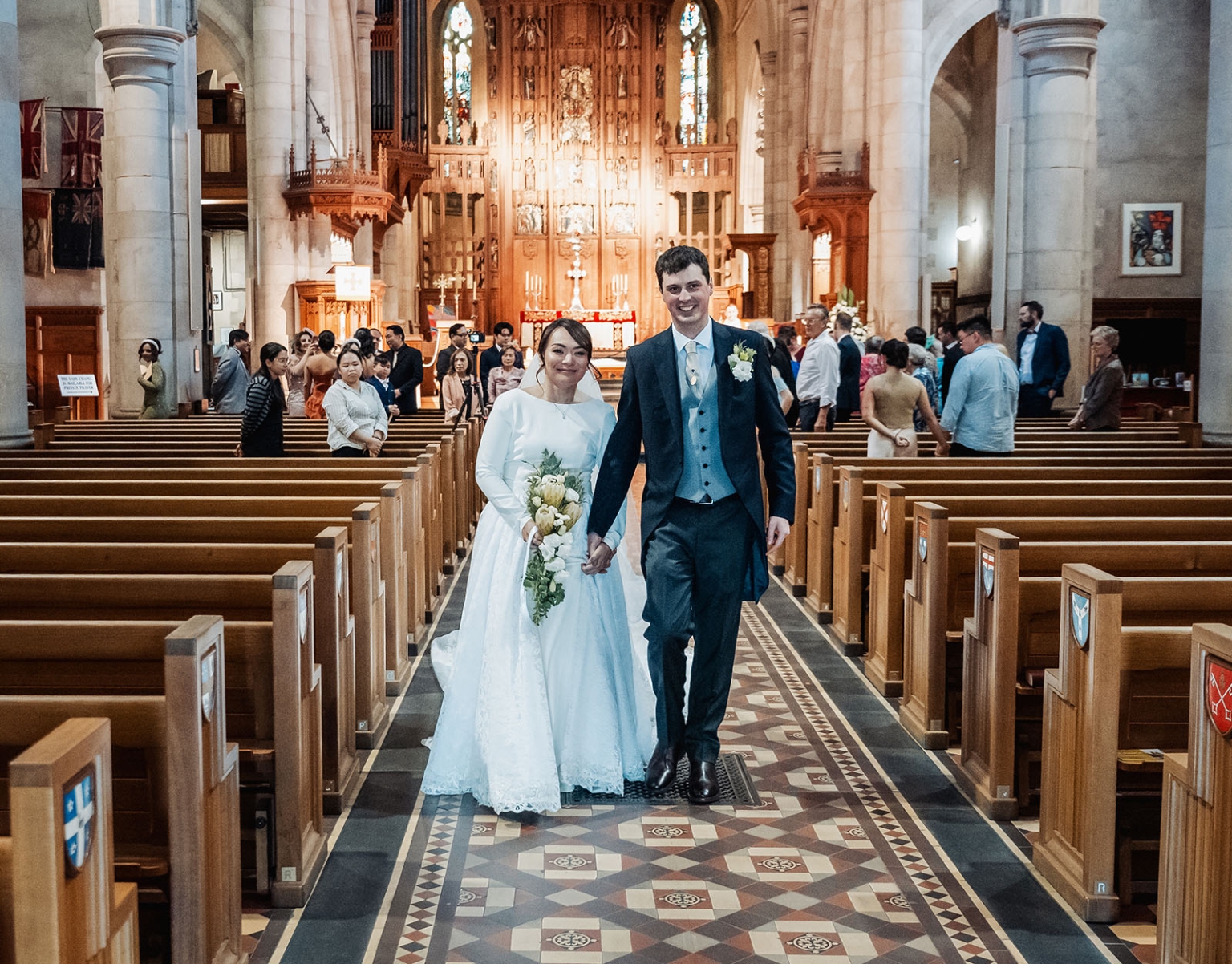 adelaide's st peter's cathedral wedding - irish & nick 29 Newlywed couple walking down church aisle after wedding ceremony.