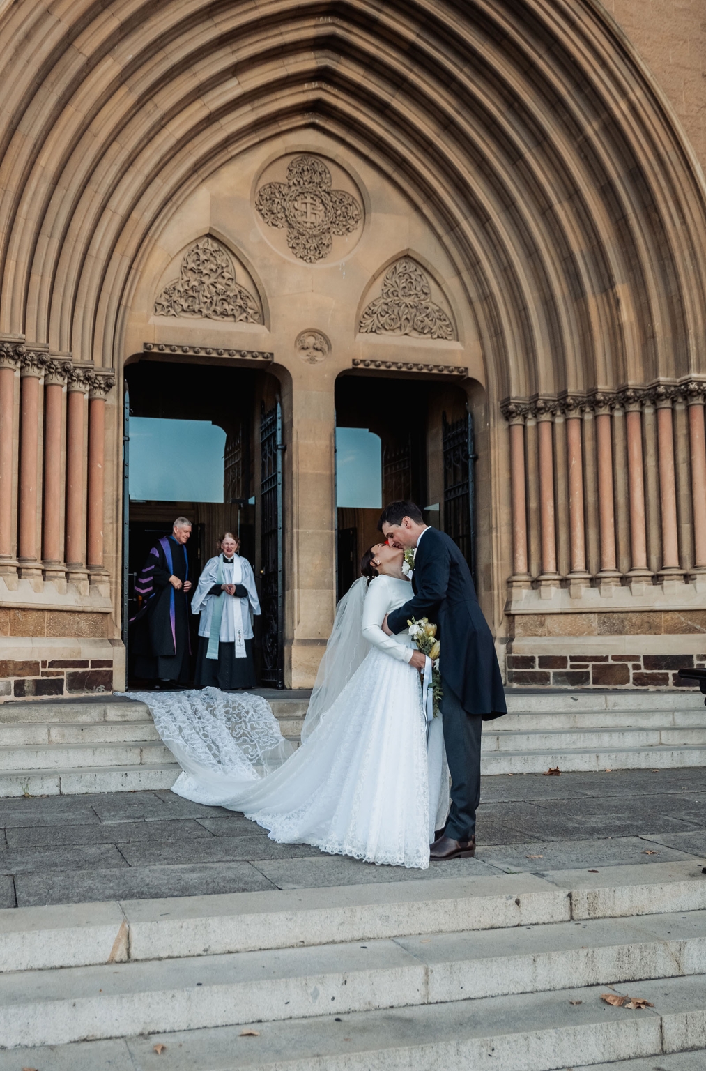 adelaide's st peter's cathedral wedding - irish & nick 30 Bride and groom kissing after church wedding outside Gothic cathedral.