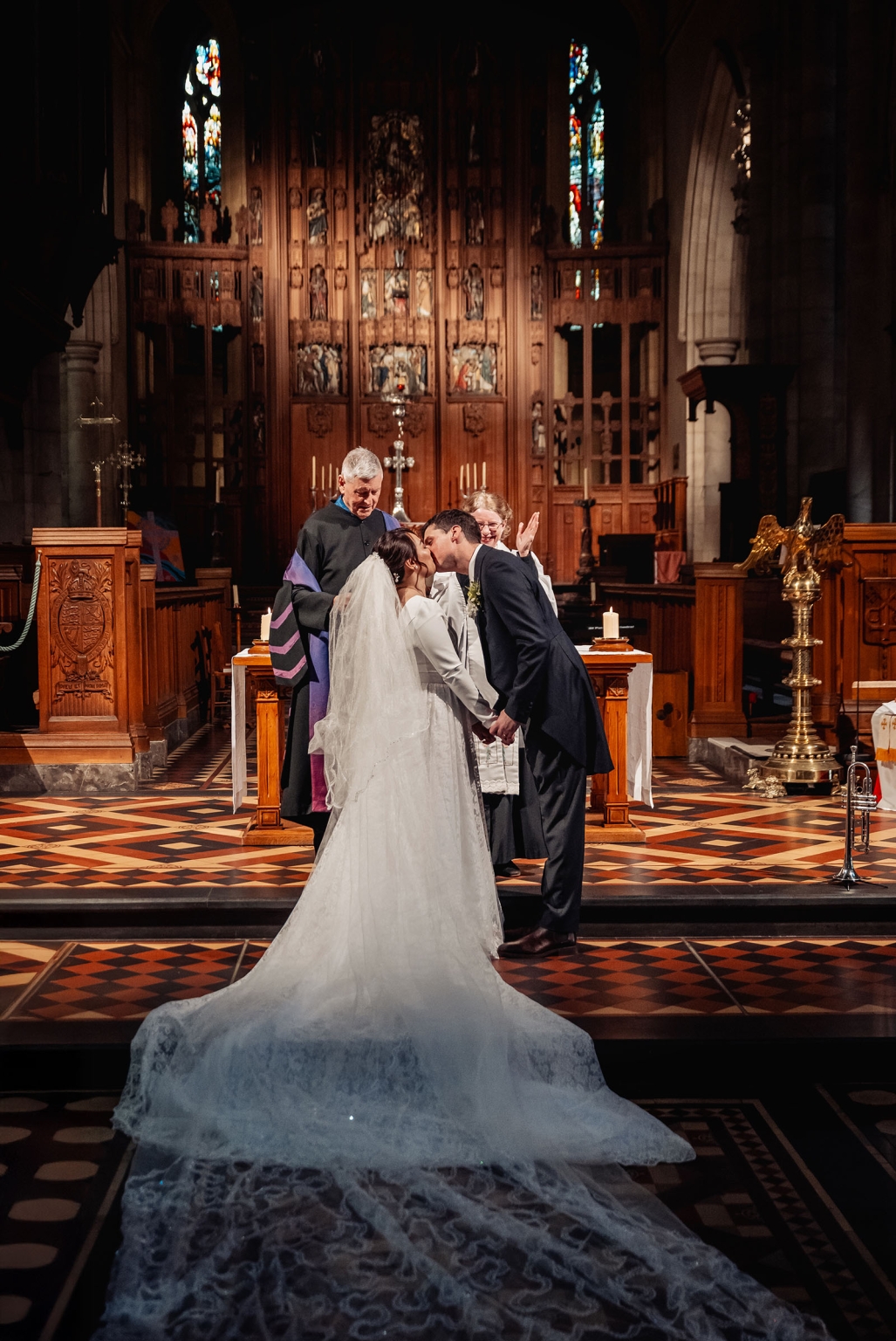 adelaide's st peter's cathedral wedding - irish & nick 25 Bride and groom kiss at cathedral altar during elegant church wedding ceremony.