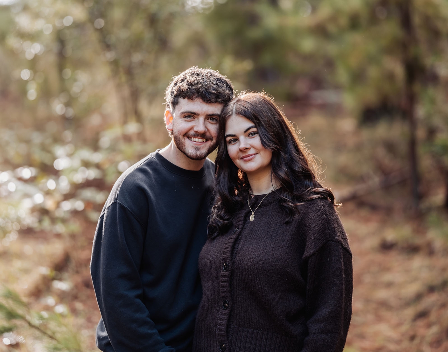 cabn at kuitpo forest proposal - tamsyn & blake 27 Couple embracing in a sunlit forest, exuding warmth and intimacy with natural surroundings.