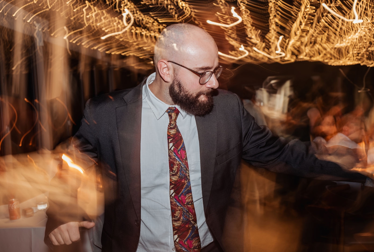 the lane vineyard wedding - caitlyn & craig 141 Man in suit dancing energetically at festive party with colorful lights.