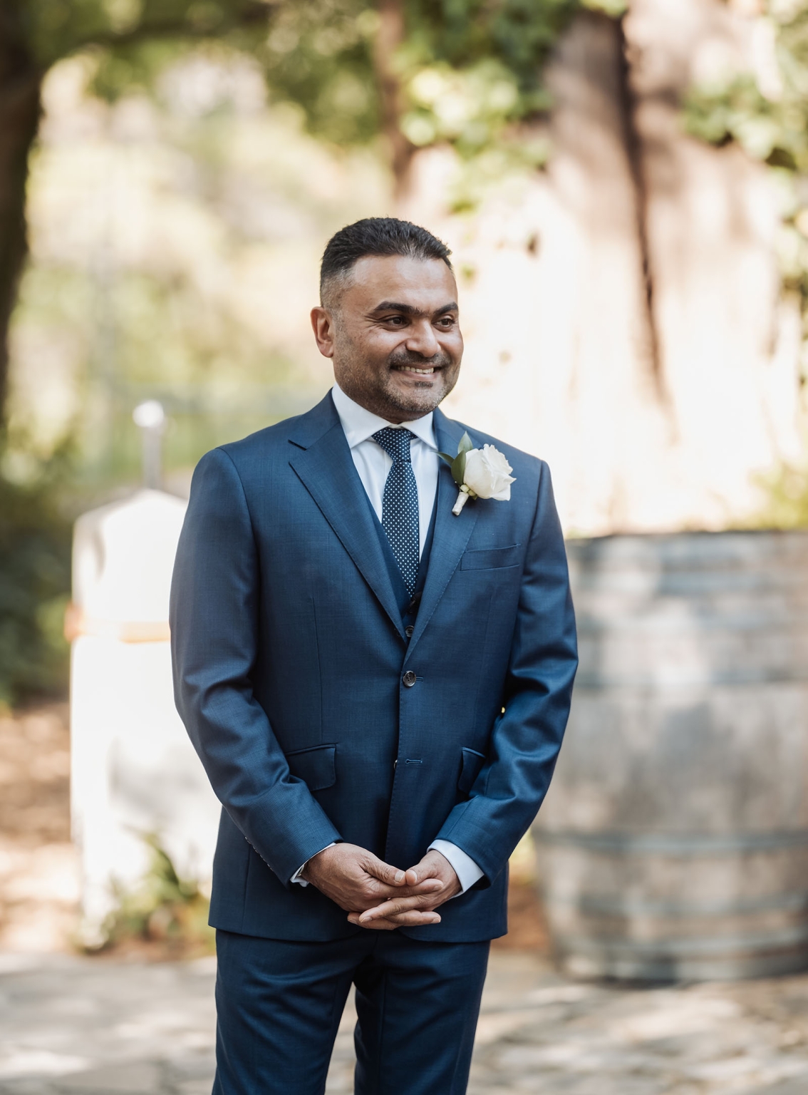 manor wedding in basket range - methmini & aravinda 131 Man in blue suit smiling in outdoor wedding or formal event setting.