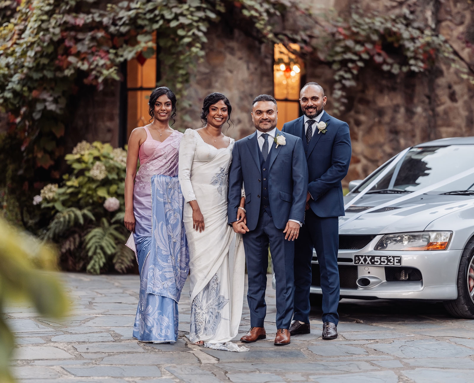 manor wedding in basket range - methmini & aravinda 157 Wedding couple and friends in elegant attire, rustic setting with a touch of modern sophistication.