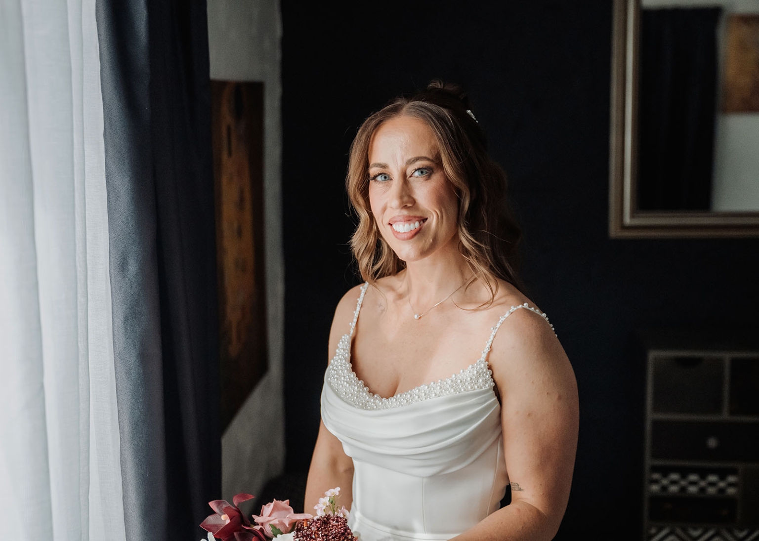 the lane vineyard wedding - caitlyn & craig 91 Bride in elegant wedding dress with bouquet by window, radiating joy.
