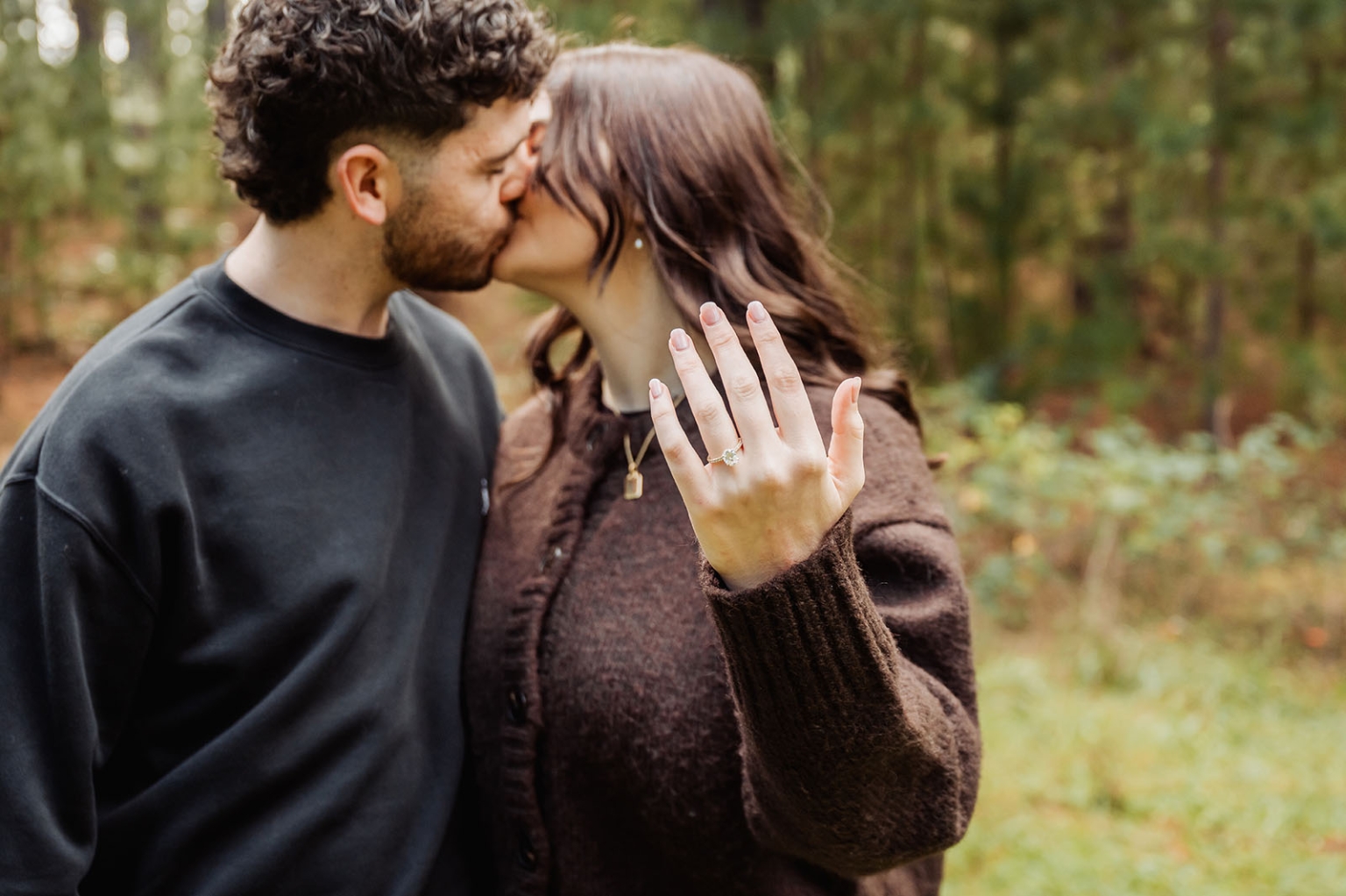 cabn at kuitpo forest proposal - tamsyn & blake 22 Couple kisses in forest, highlighting engagement ring amid lush greenery.