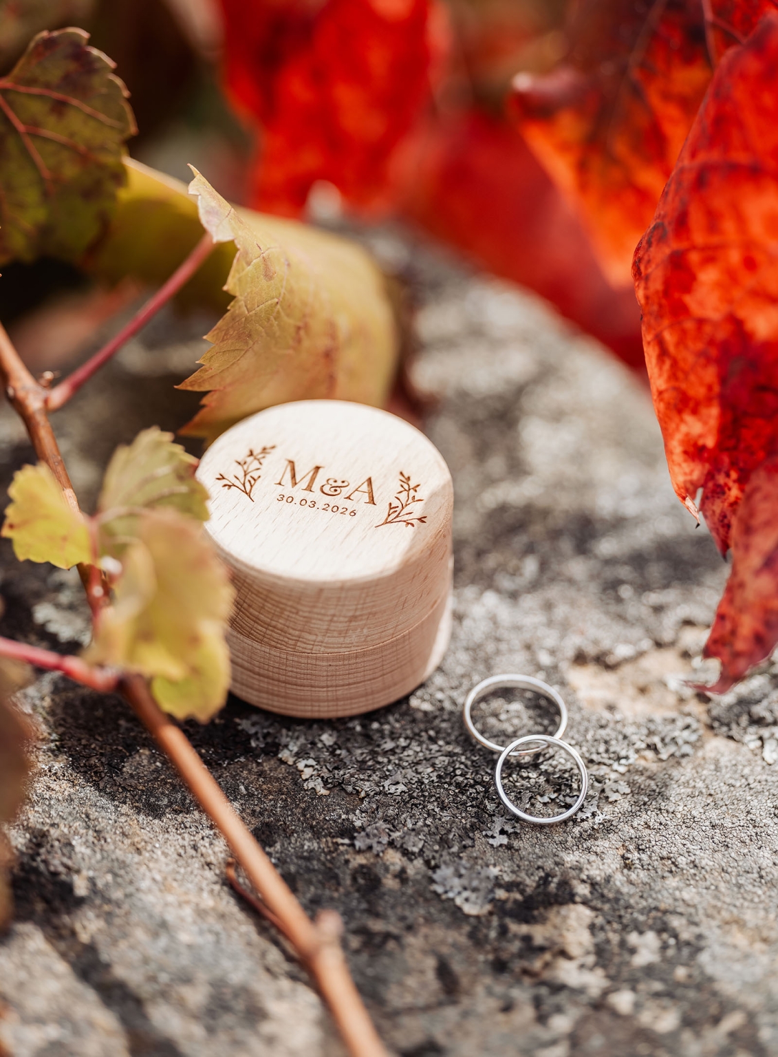 manor wedding in basket range - methmini & aravinda 105 Engraved wooden box and silver rings amidst autumn leaves, symbolizing love and commitment.