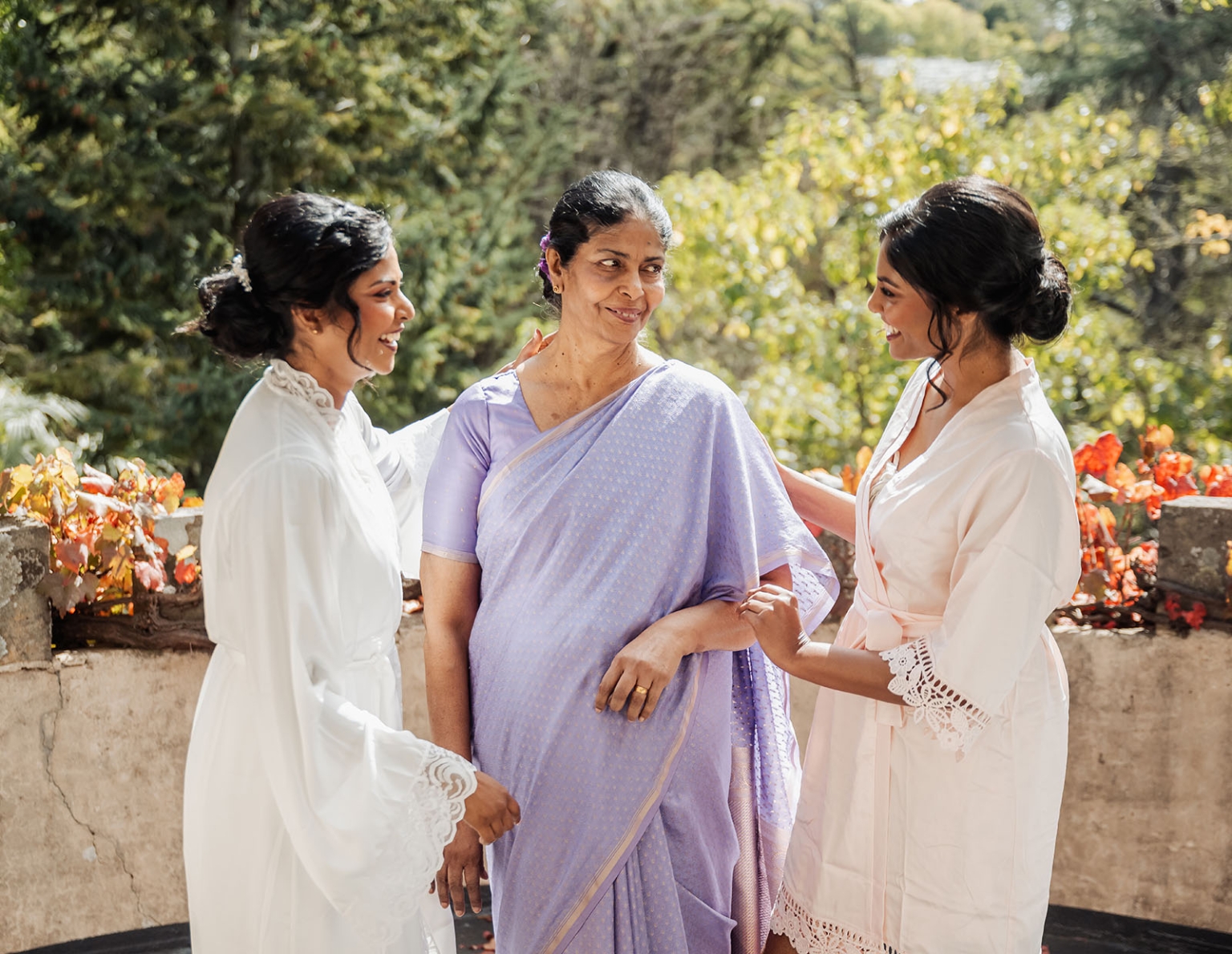 manor wedding in basket range - methmini & aravinda 113 Three women bonding on a balcony with lush greenery and autumn colors.