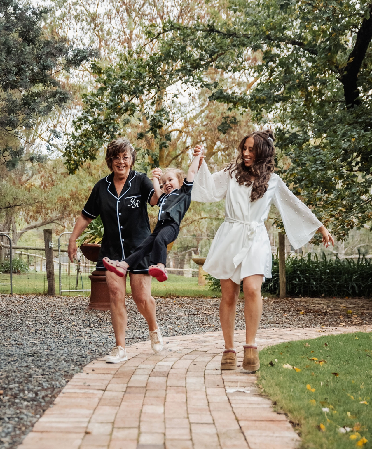 the lane vineyard wedding - caitlyn & craig 85 Family enjoying a joyful moment, swinging child on garden path surrounded by nature.