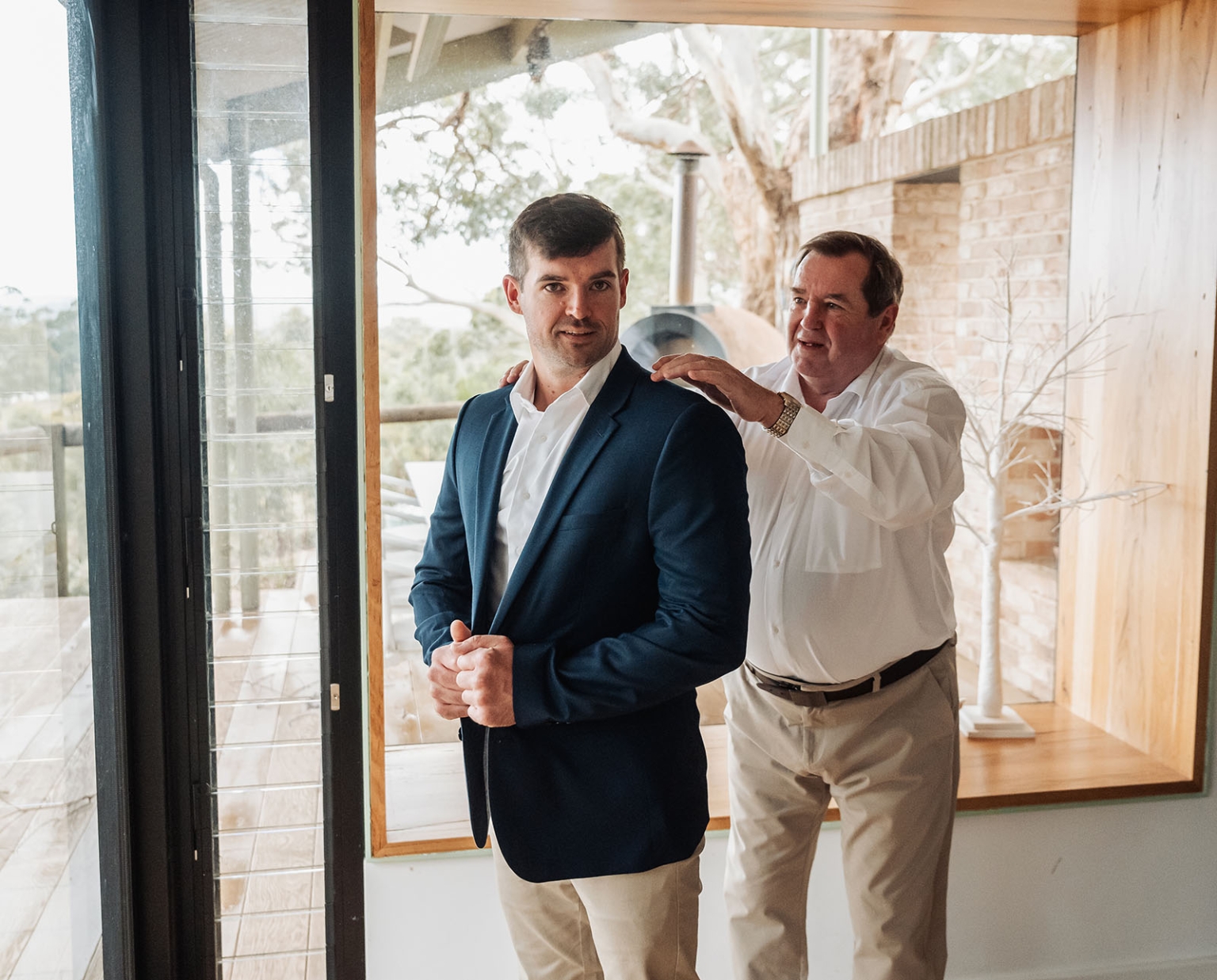 the lane vineyard wedding - caitlyn & craig 66 Father and son bonding before event, dressed in formal attire, in a modern, cozy setting.