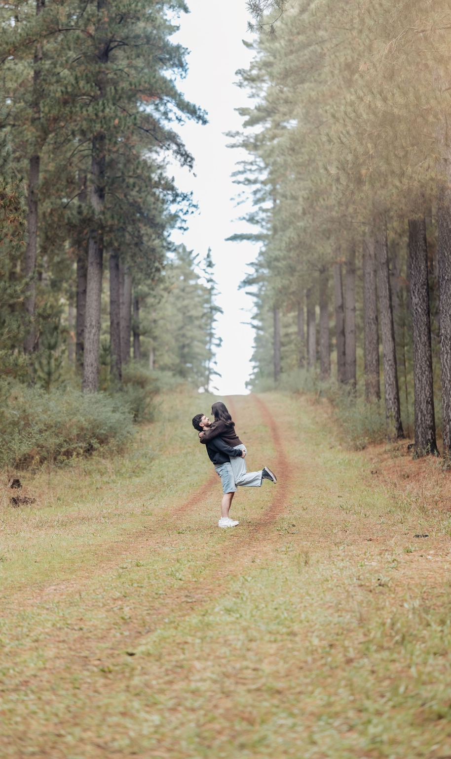 cabn at kuitpo forest proposal - tamsyn & blake 17 Couple embracing on a lush forest path under tall trees.