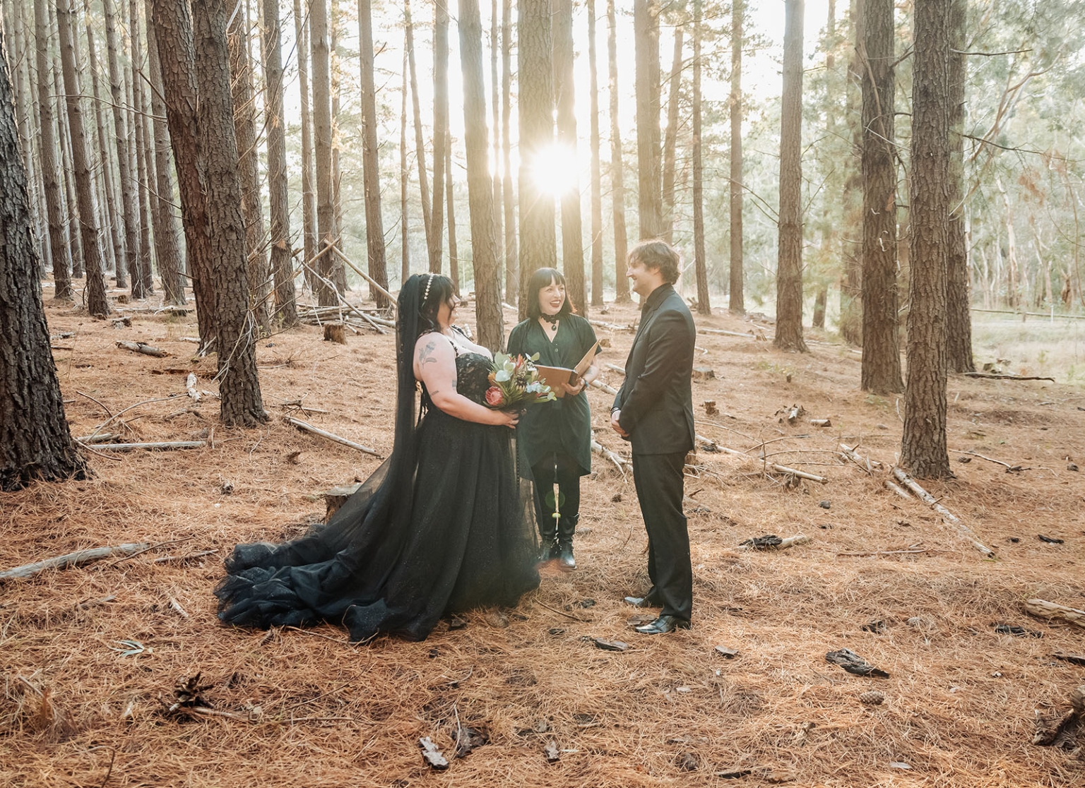 kuitpo forest metal themed wedding – erin & michael 5 Black wedding dress forest elopement ceremony with groom and officiant in pine woods.