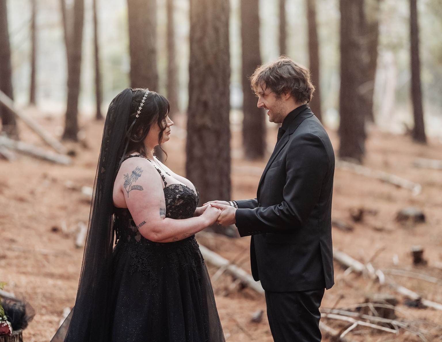 kuitpo forest metal themed wedding – erin & michael 11 Gothic forest wedding couple in black attire holding hands among pine trees.