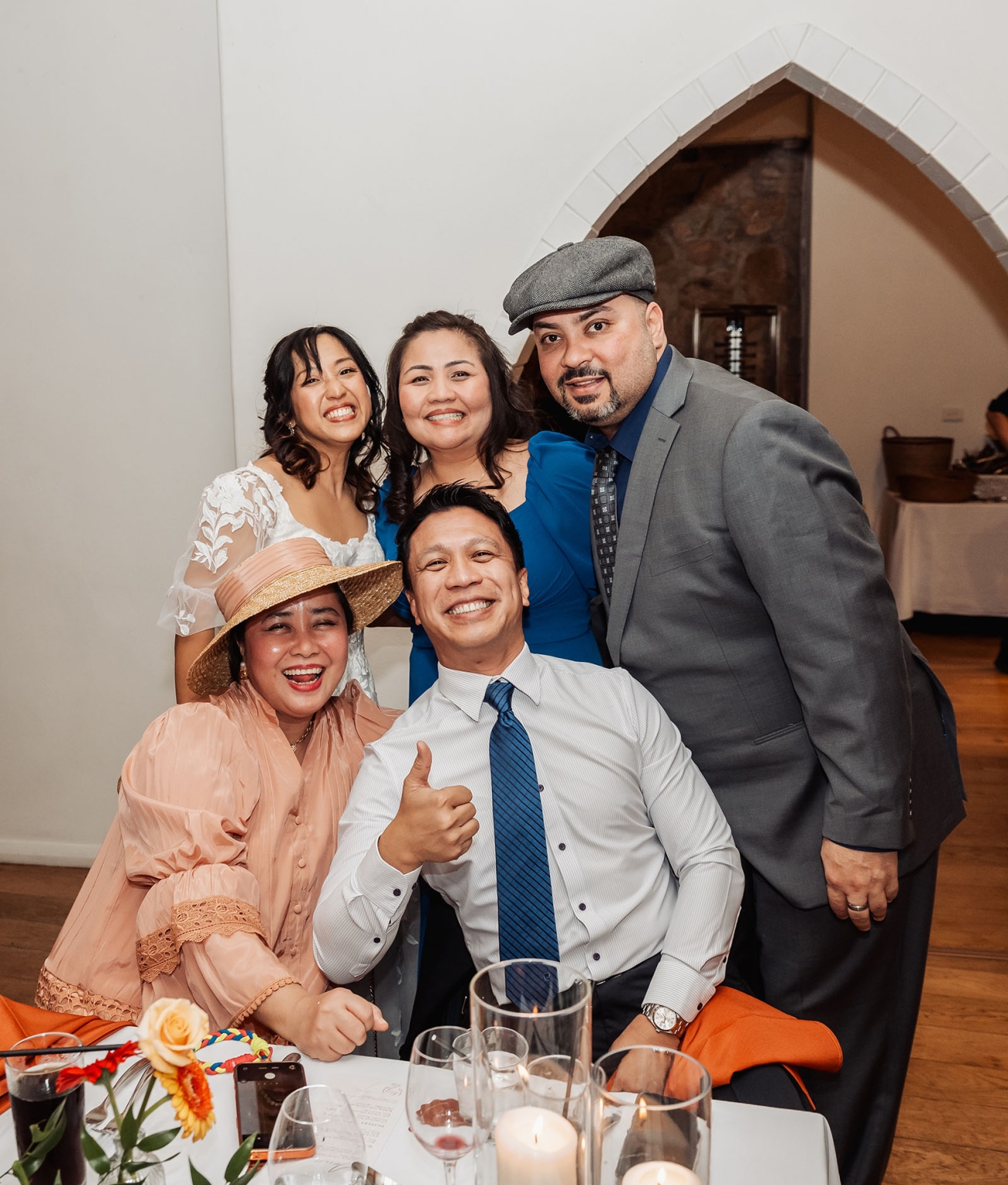 adelaide hills wedding at the manor - jo & dan 63 Happy wedding reception group portrait with formally dressed friends at decorated dining table.