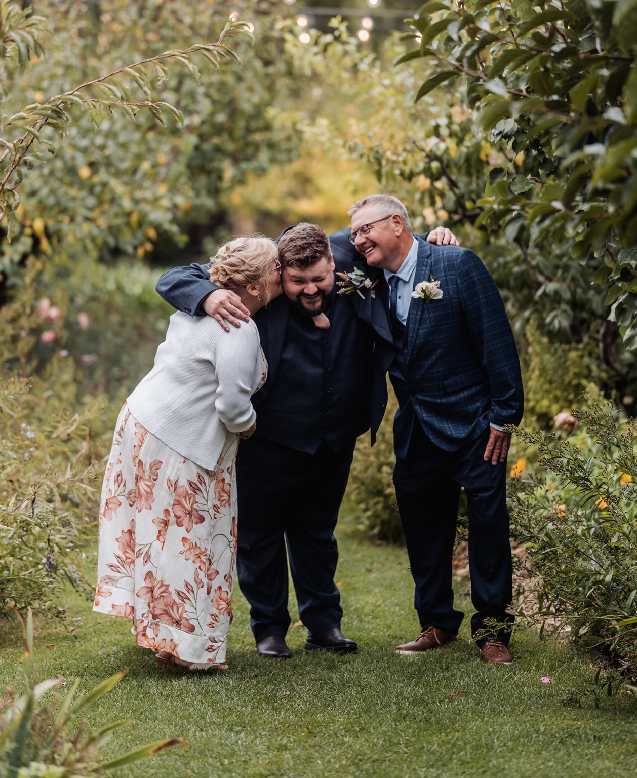 comida wedding - georgia & james 26 Family celebrating in a lush garden with joyful embraces and elegant attire.