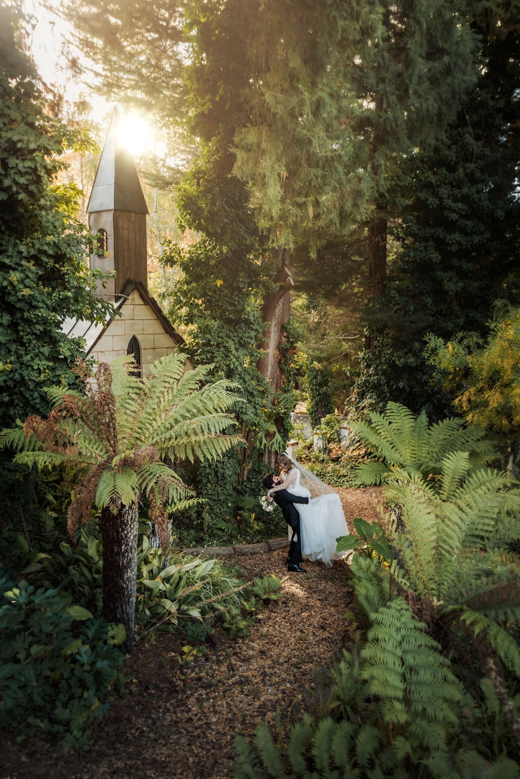 beautiful manor basket range wedding - sophie & theodore 114 Romantic garden wedding scene with couple embracing near a charming chapel.