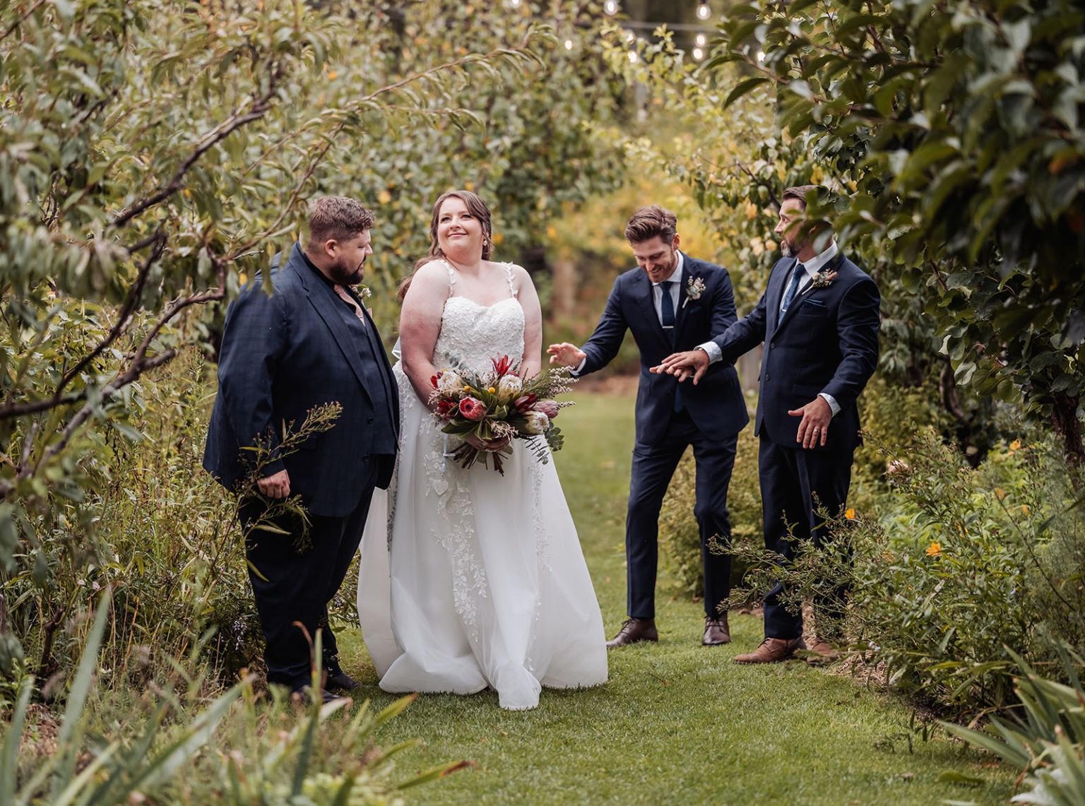 comida wedding - georgia & james 33 Joyful outdoor wedding with bride, groomsmen, vibrant garden setting, and festive lights.