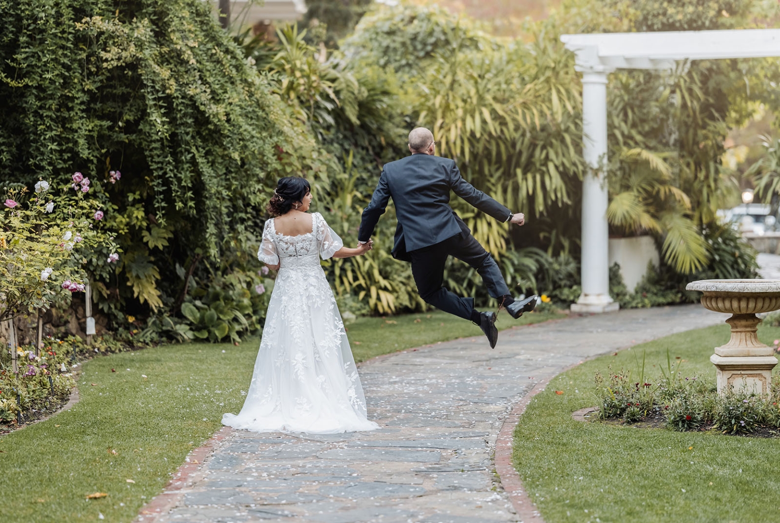 adelaide hills wedding at the manor - jo & dan 37 Joyful bride and groom walking through romantic garden wedding path.